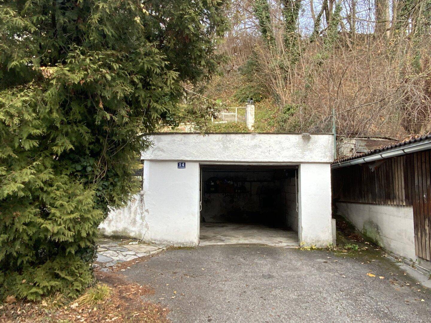 Leere Garage mit offenem Tor und Zufahrt.