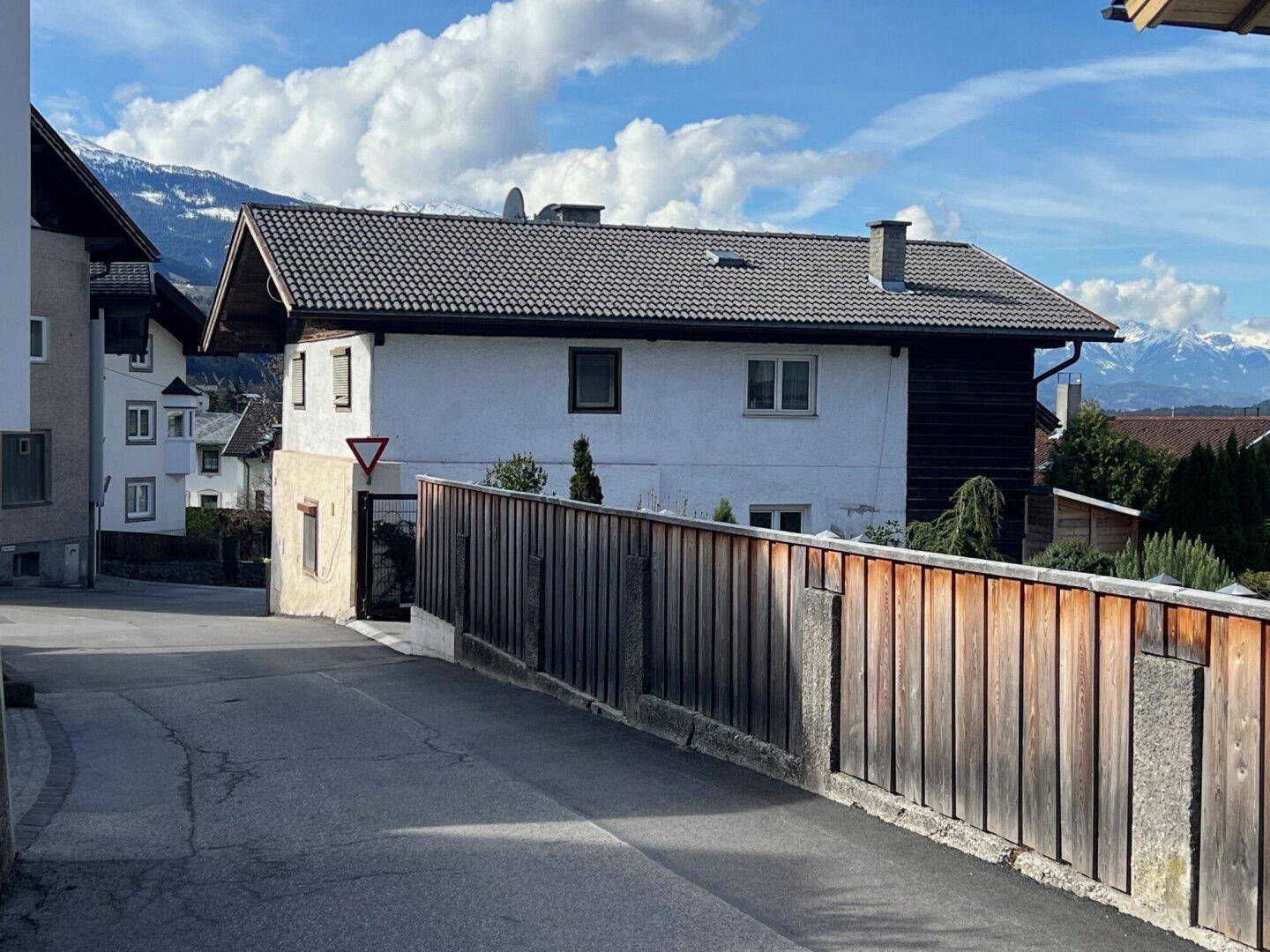 Traditionelles Wohnhaus mit Satteldach und Holzelementen an einer ruhigen Straße gelegen.