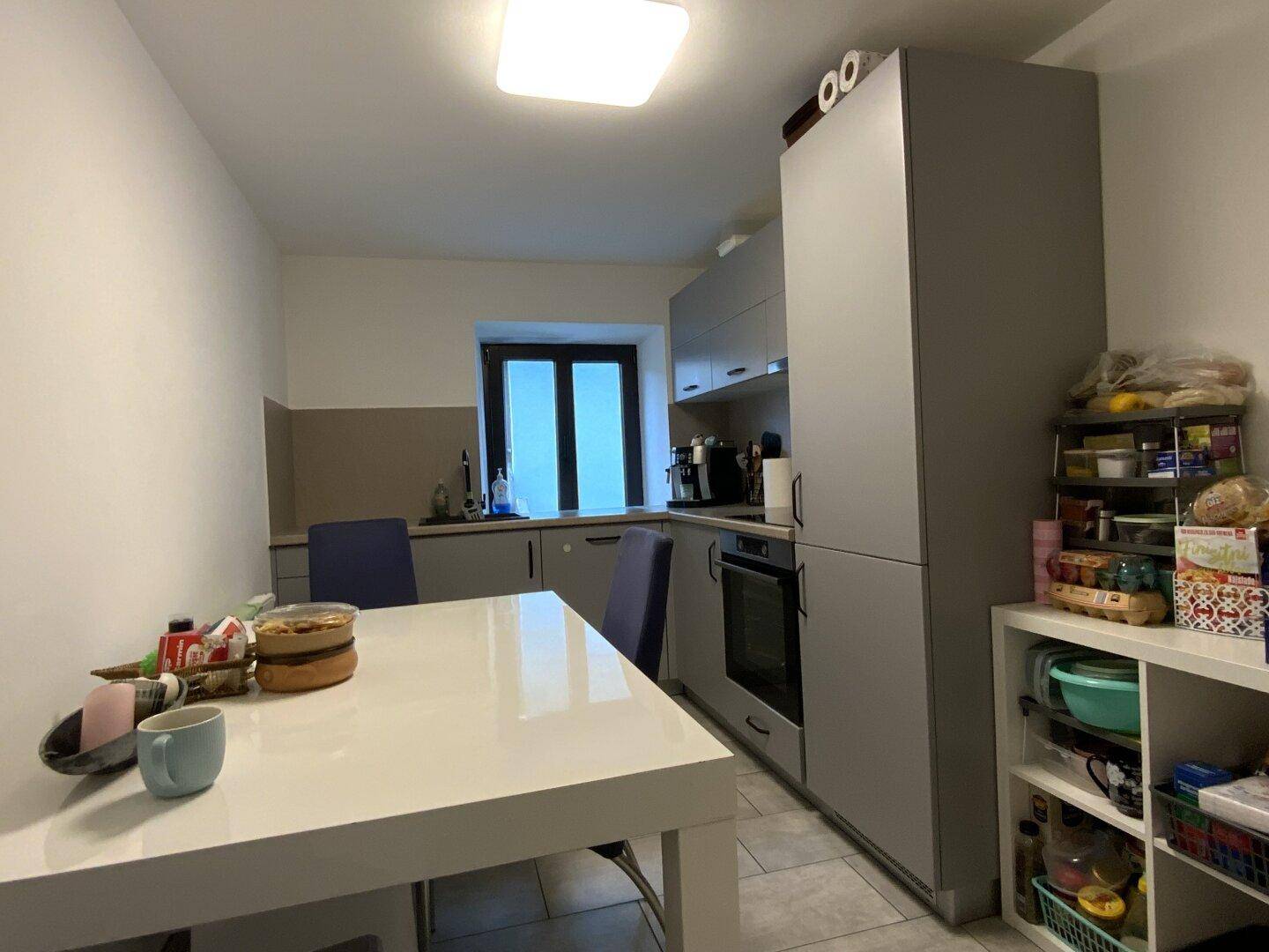 Geräumige Wohnküche mit Esstisch, grauen Einbauschränken und praktischem Stauraum.