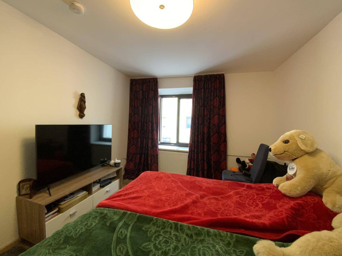 Helles Schlafzimmer mit bequemen Betten, einem Fernseher und Laminatboden.