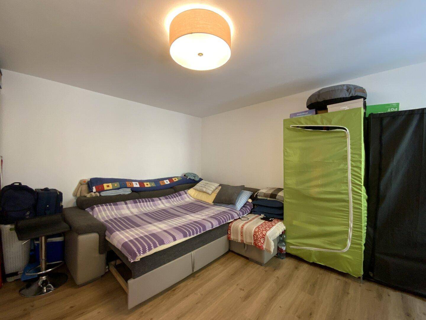 Gemütliches Wohnzimmer mit Schlafsofa, Laminatboden und praktischem Stauraum.