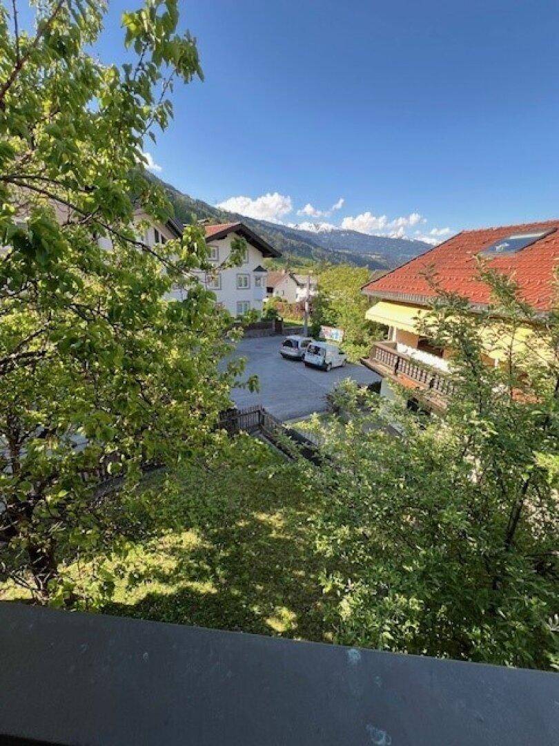 Weitblick über die Nachbarschaft mit Parkplatz und beeindruckendem Bergpanorama im Hintergrund.