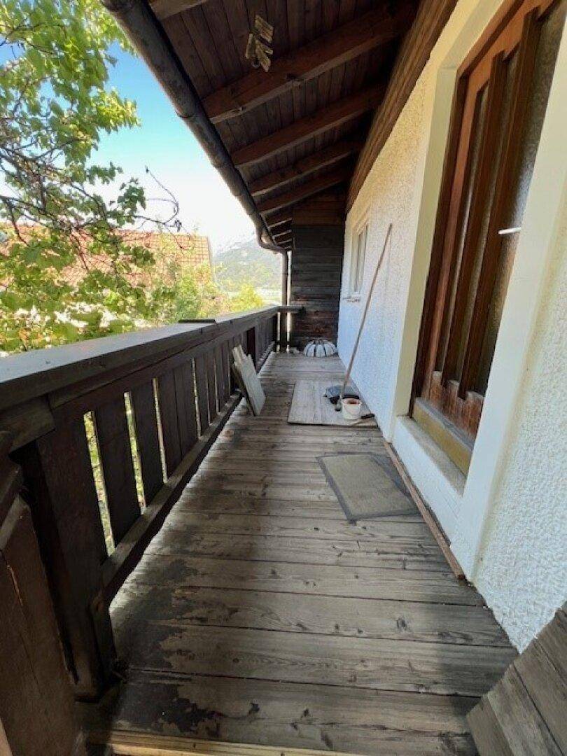 Langer Holzbalkon mit traditionellem Geländer und Blick auf die umliegende Natur.