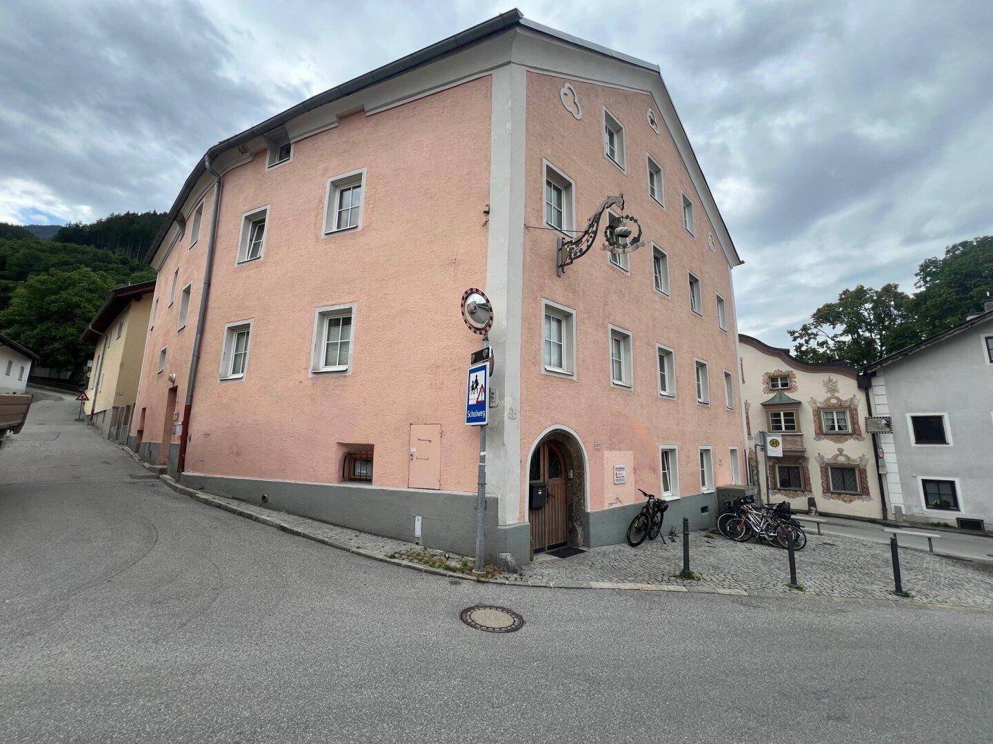 Die rosafarbene Fassade des historischen Gebäudes mit dem Haupteingang und dekorativen Elementen.