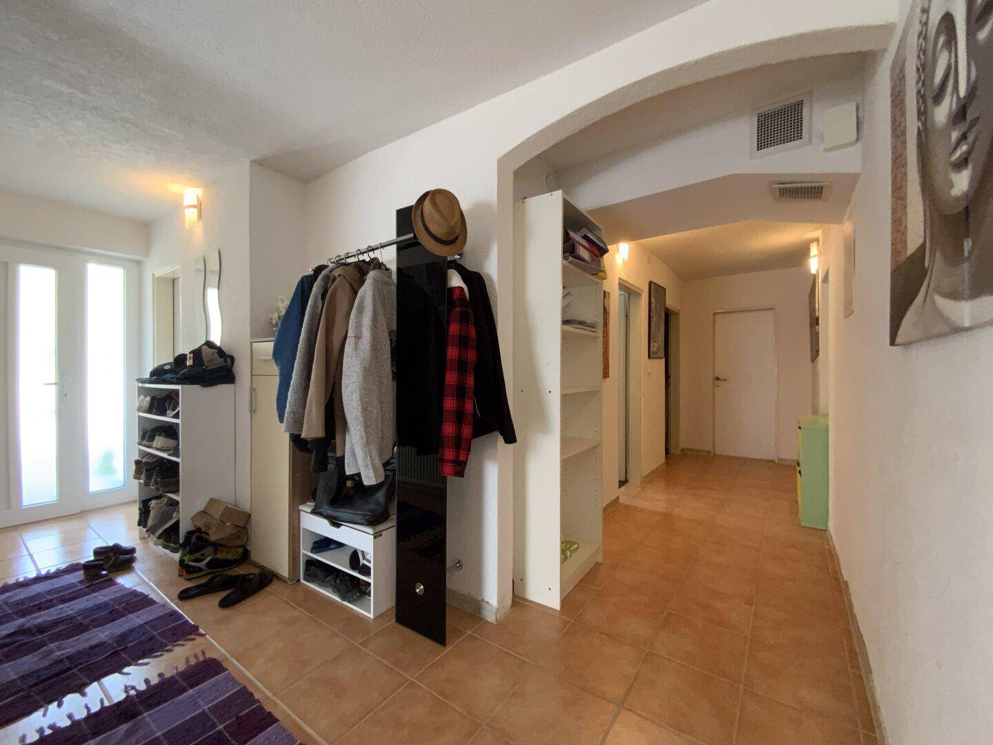 Geräumiger Flur mit Fliesenboden, Garderobe und offenem Durchgang zu weiteren Räumen.