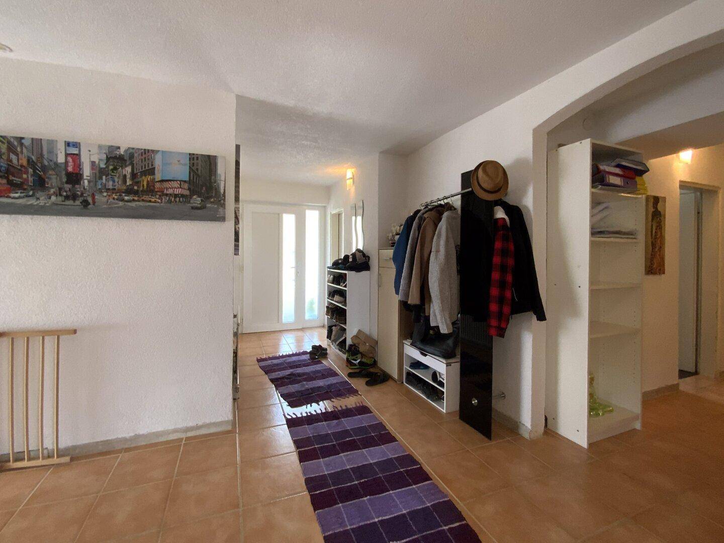 Heller Flur mit Fliesenboden, Garderobe und Zugang zu den Wohnbereichen.