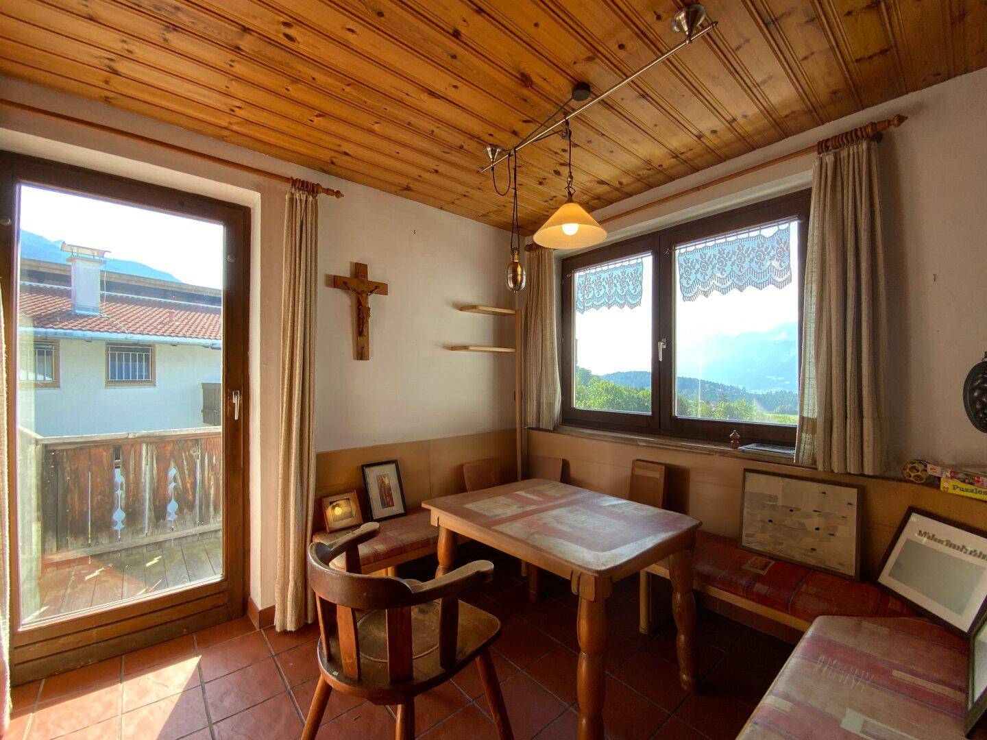 Essbereich mit Holztisch, Eckbank und Balkonzugang, bietet einen weiten Blick.