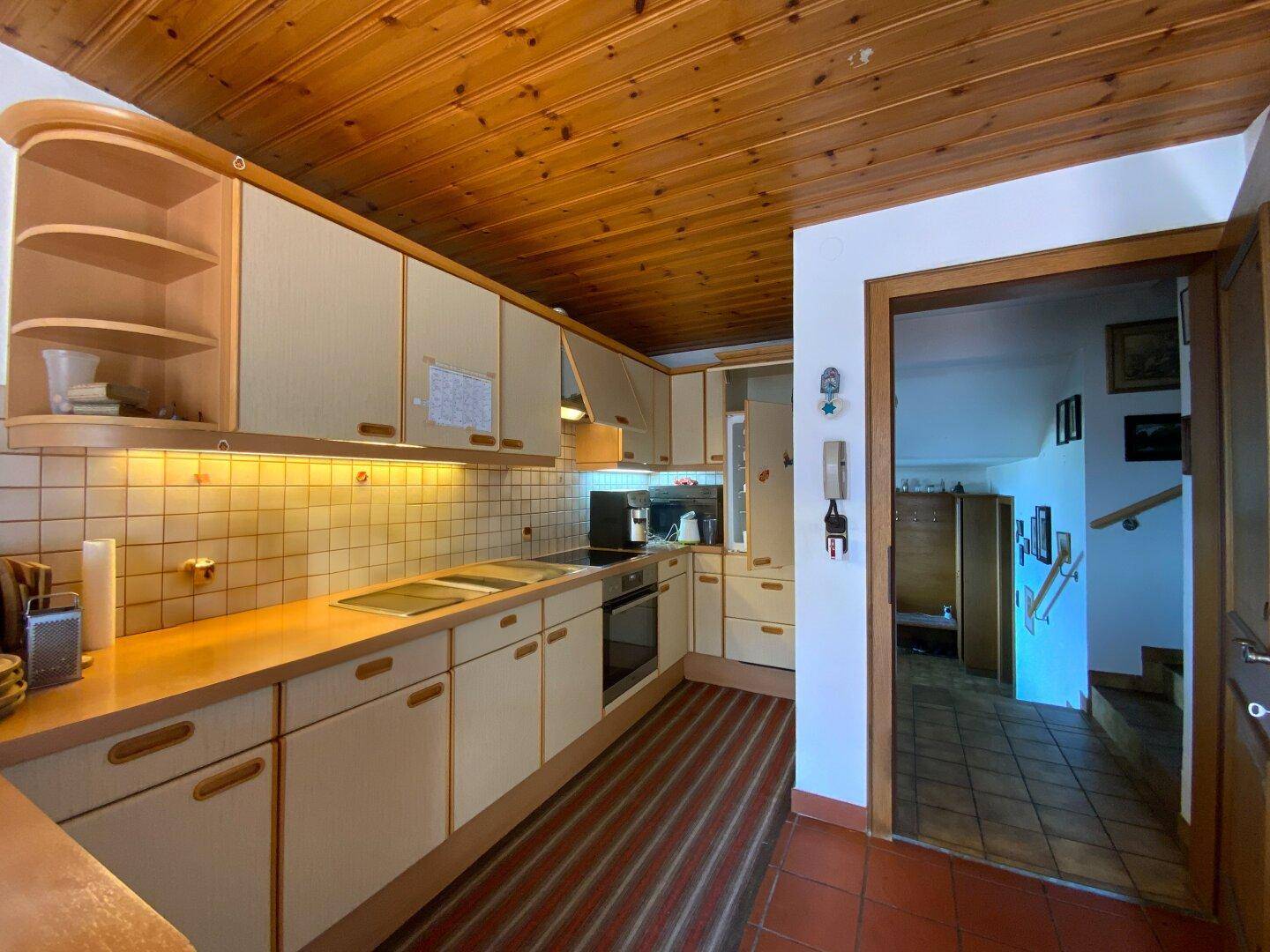 Funktionale Küche mit Holzdecke, Einbaugeräten und gefliestem Arbeitsbereich.