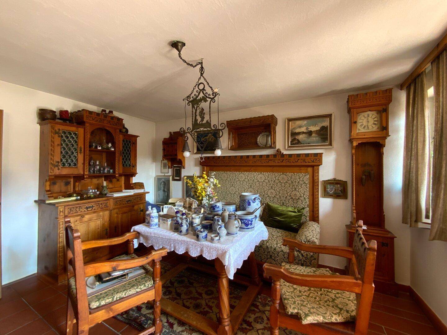 Traditioneller Essbereich mit antiken Holzmöbeln, reich verzierter Deckenleuchte und Teppich.