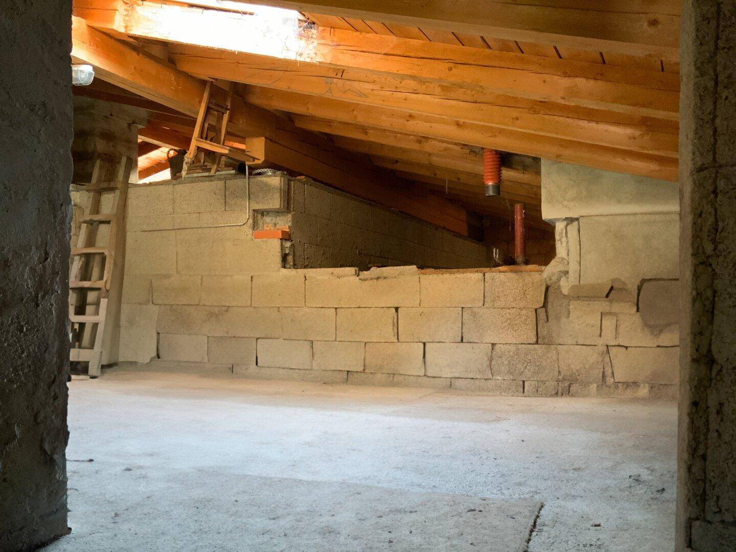 Unausgebauter Dachboden mit sichtbaren Holzbalken und Mauerwerk, bietet Ausbaupotenzial.