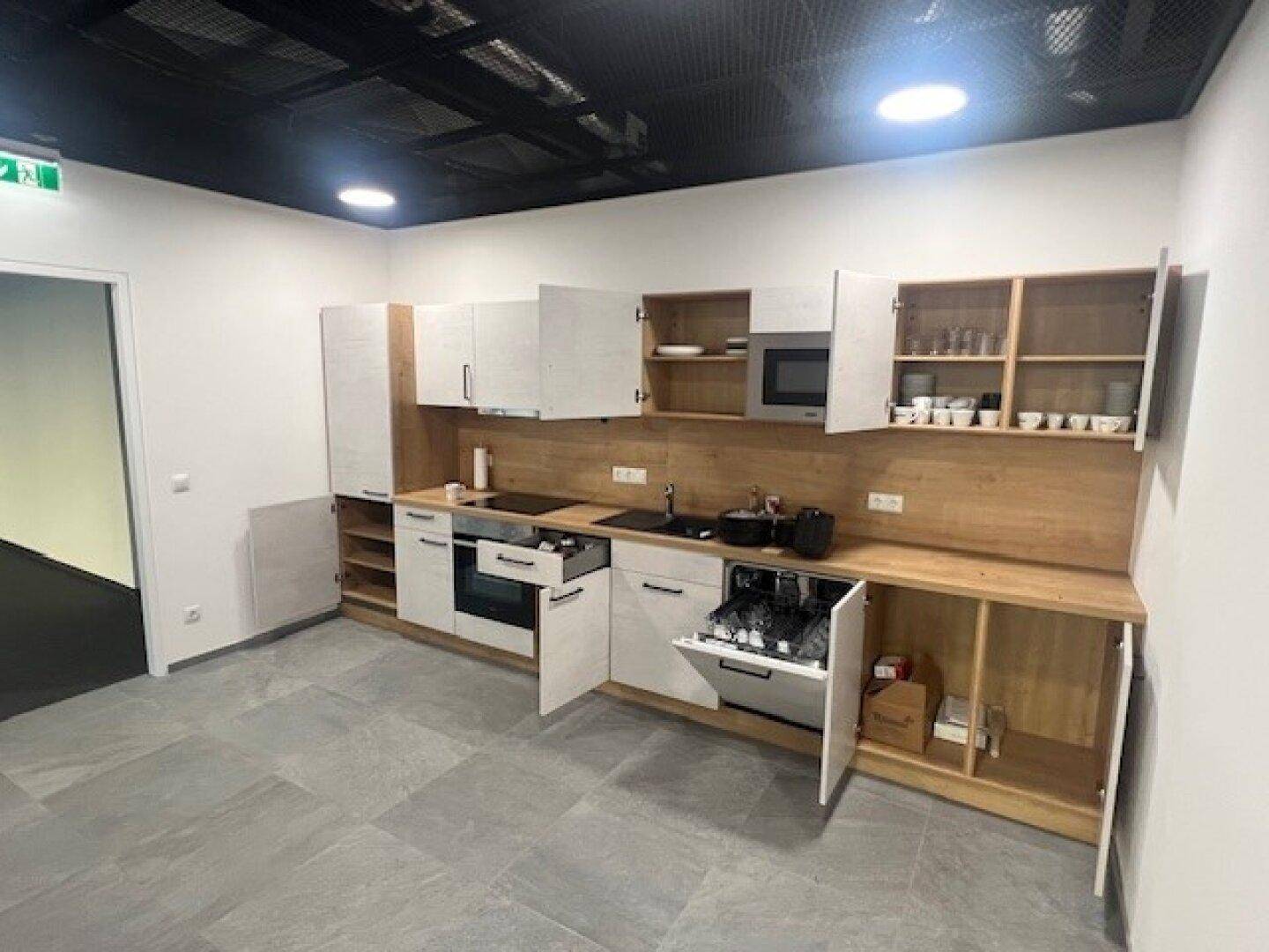 Moderne Einbauküche mit hellen Holz- und weißen Fronten, ausgestattet mit Geschirrspüler und Mikrowelle.