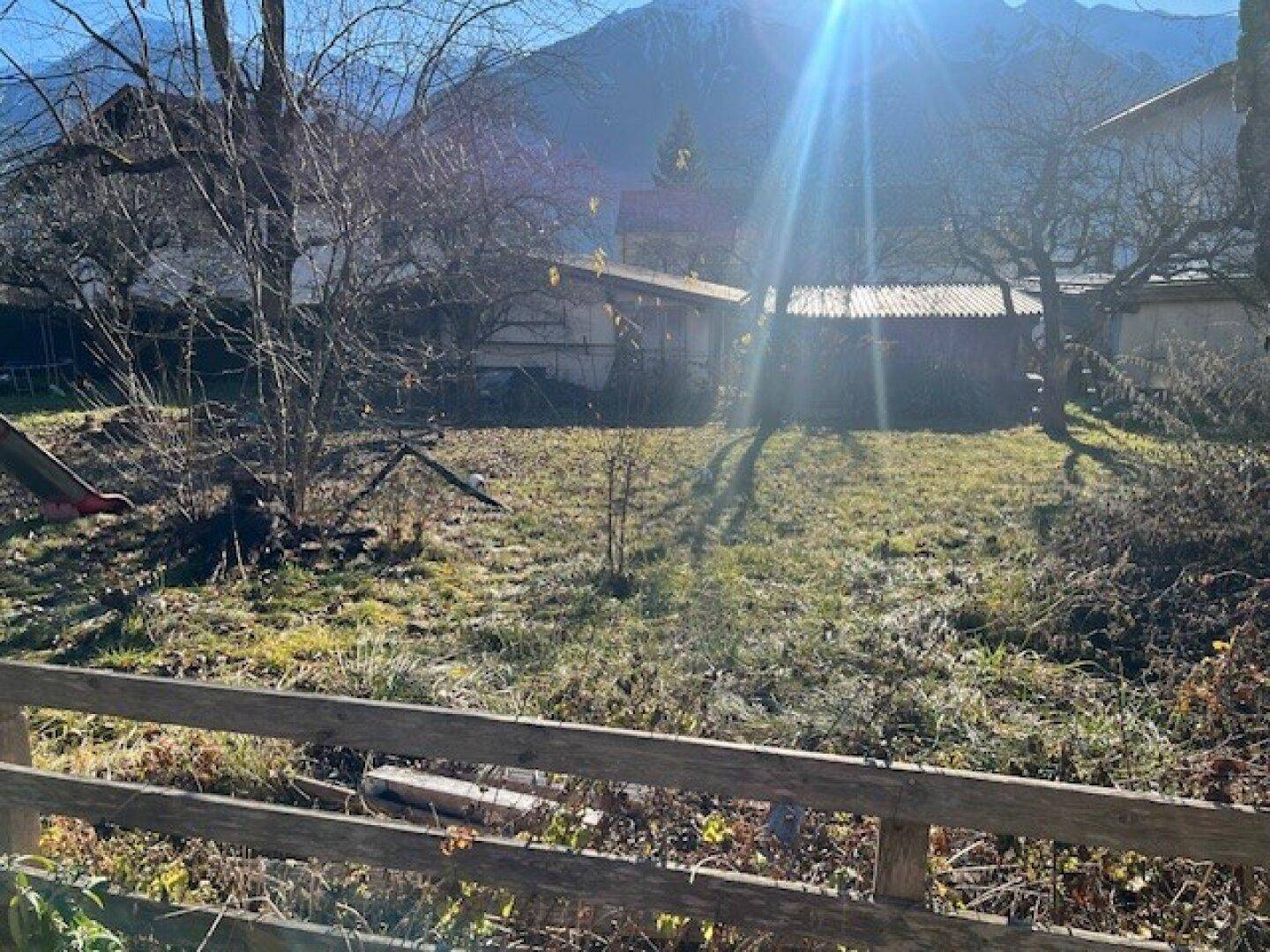 Weitläufiger Garten mit altem Baumbestand und sonnigem Blick auf die Berge.