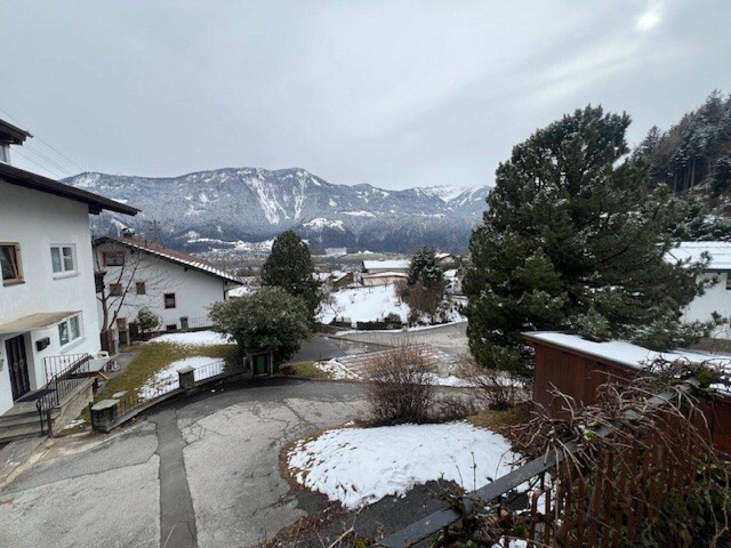 Panoramablick auf die verschneite Landschaft mit Häusern und hohen Nadelbäumen.