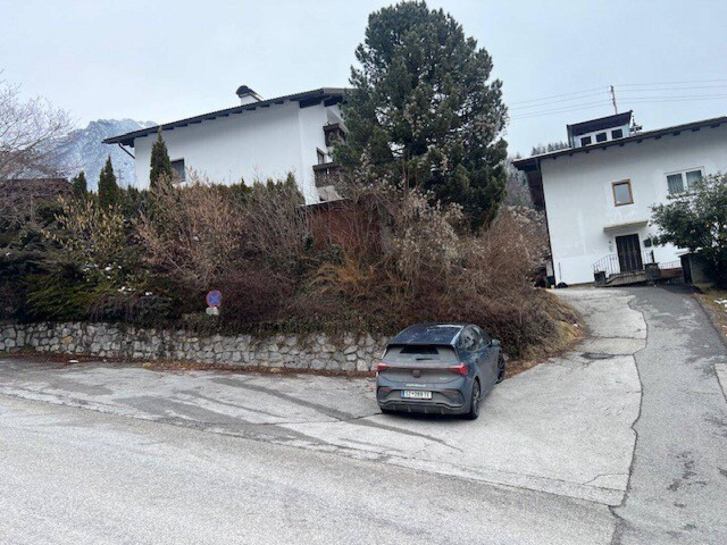 Blick auf die Straße und die Umgebung mit einem geparkten Auto und Häusern.
