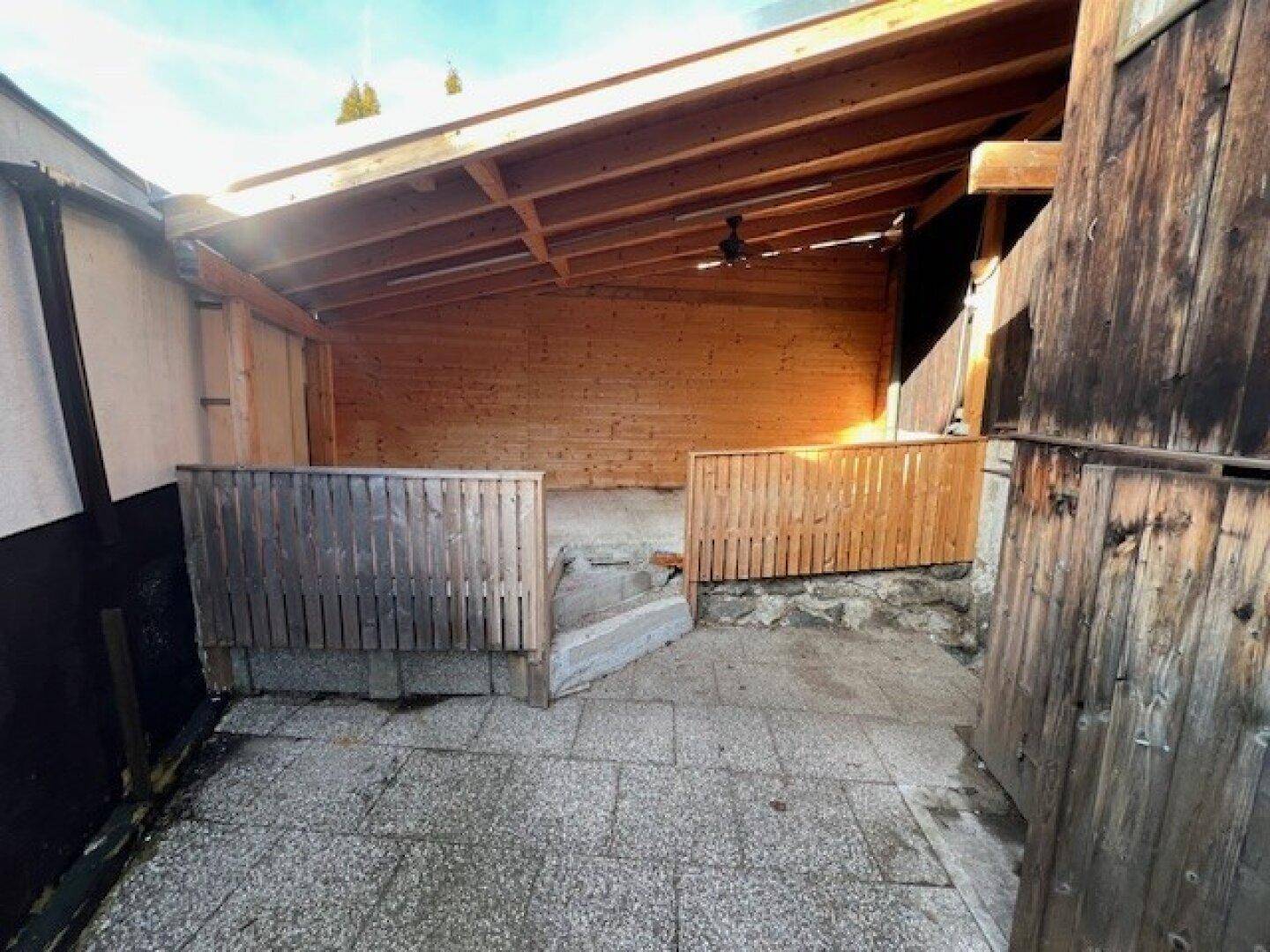 Überdachter Außenbereich mit Steinplattenboden und Holzwänden, ideal für gesellige Stunden.