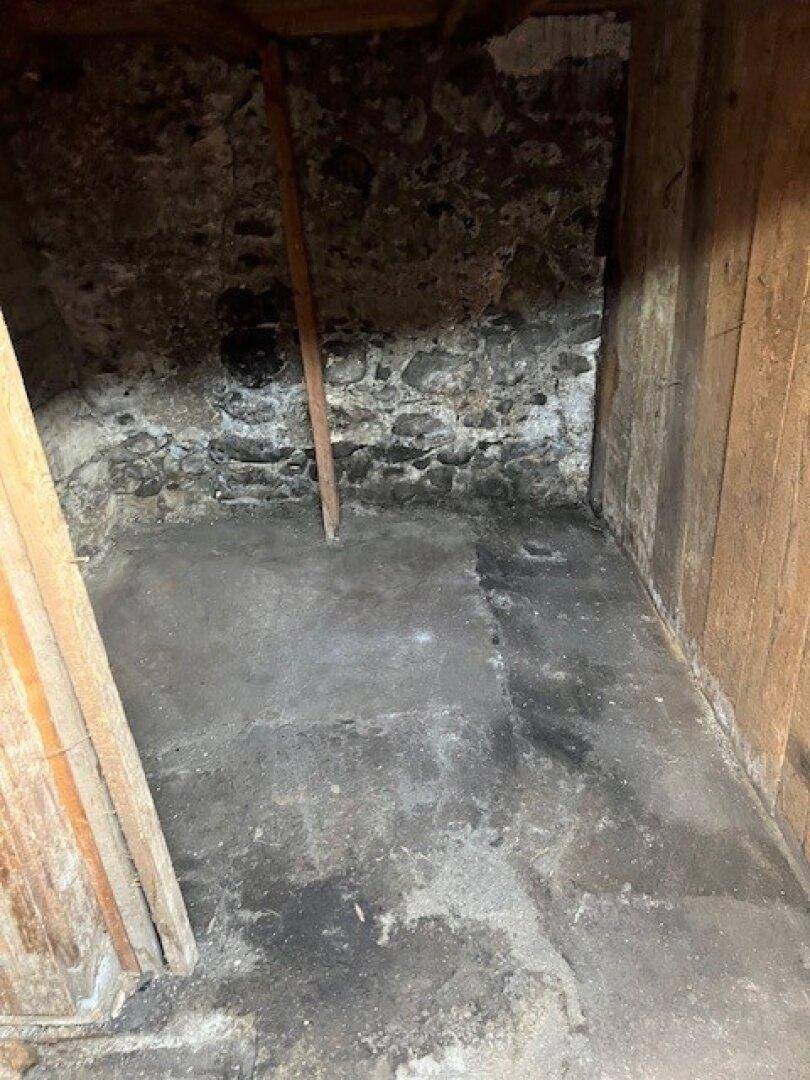 Einfacher Kellerraum mit Steinwänden und Betonboden, ideal für Lagerzwecke.