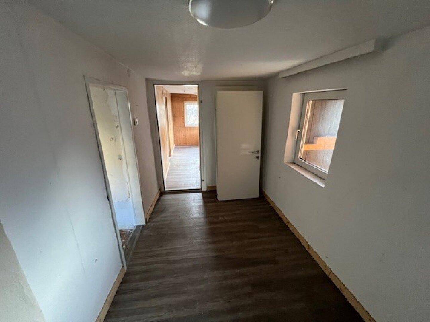 Heller Flur mit neuem Laminatboden und Türen zu angrenzenden Räumen.
