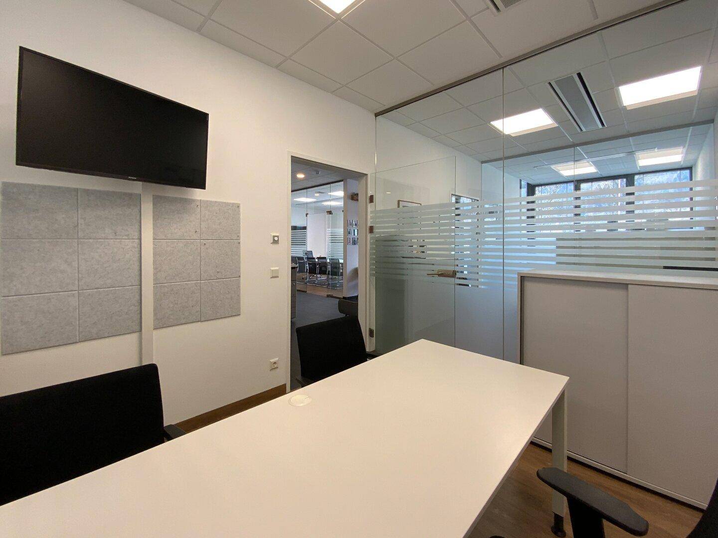 Büro mit Schreibtisch, Bürostühlen und schallabsorbierenden Wandpaneelen.