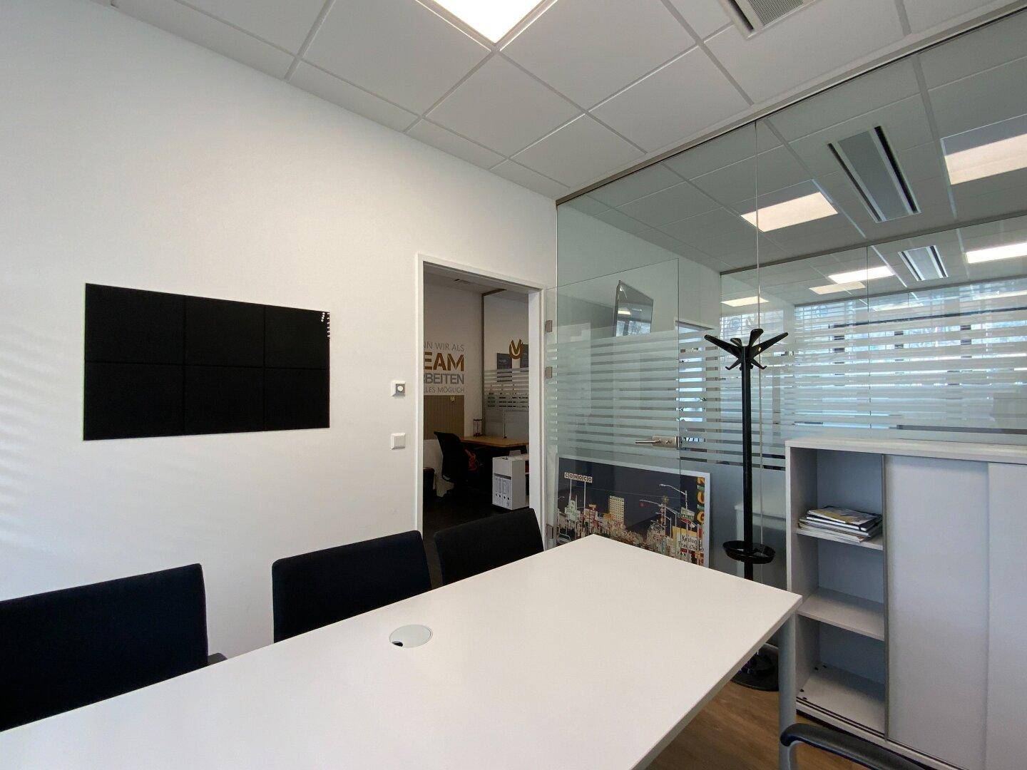 Büro mit Schreibtisch, Bürostühlen und Garderobenständer.