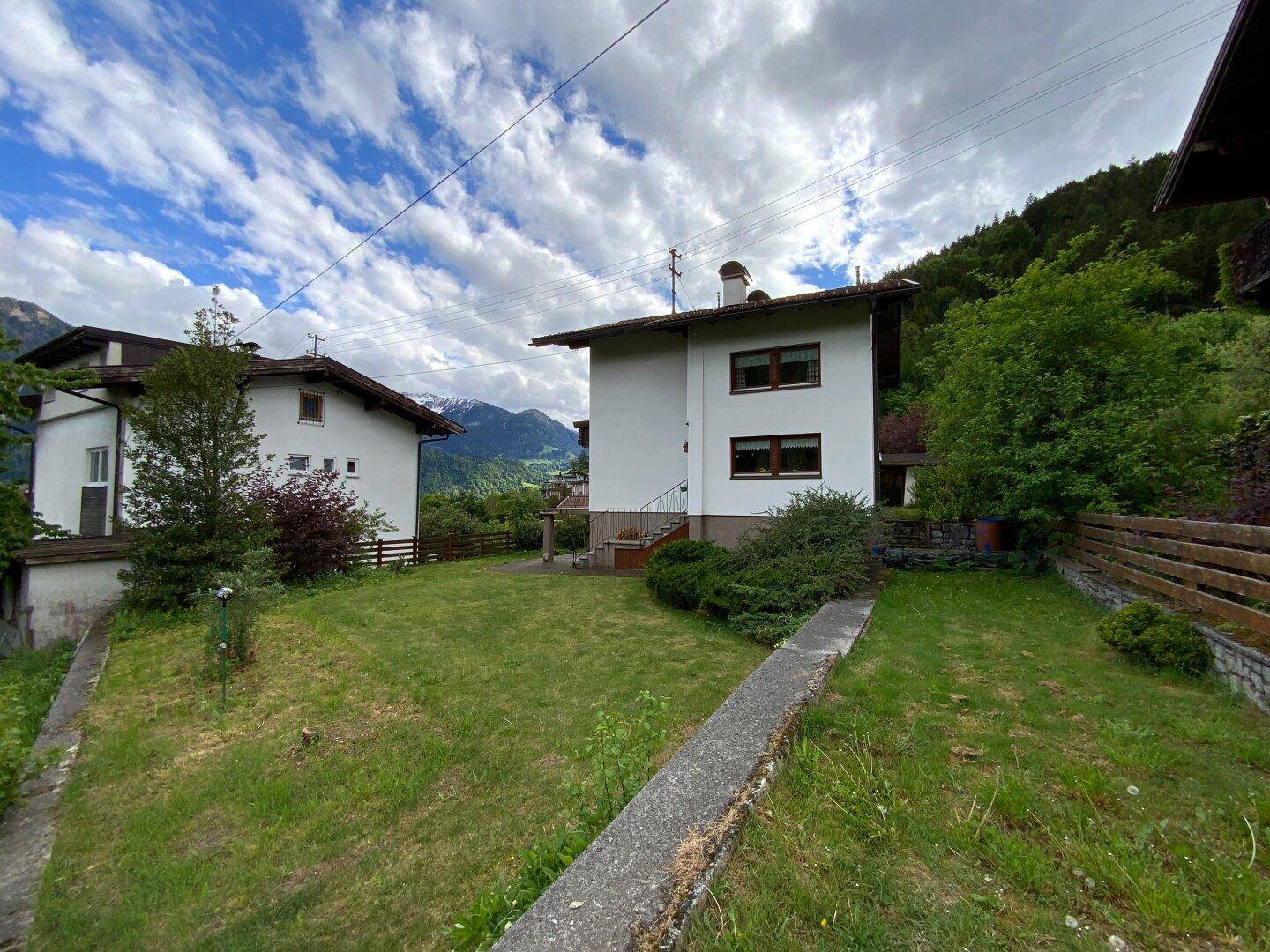 Rückansicht des Hauses mit angrenzendem Garten und Blick auf die umliegende Berglandschaft.