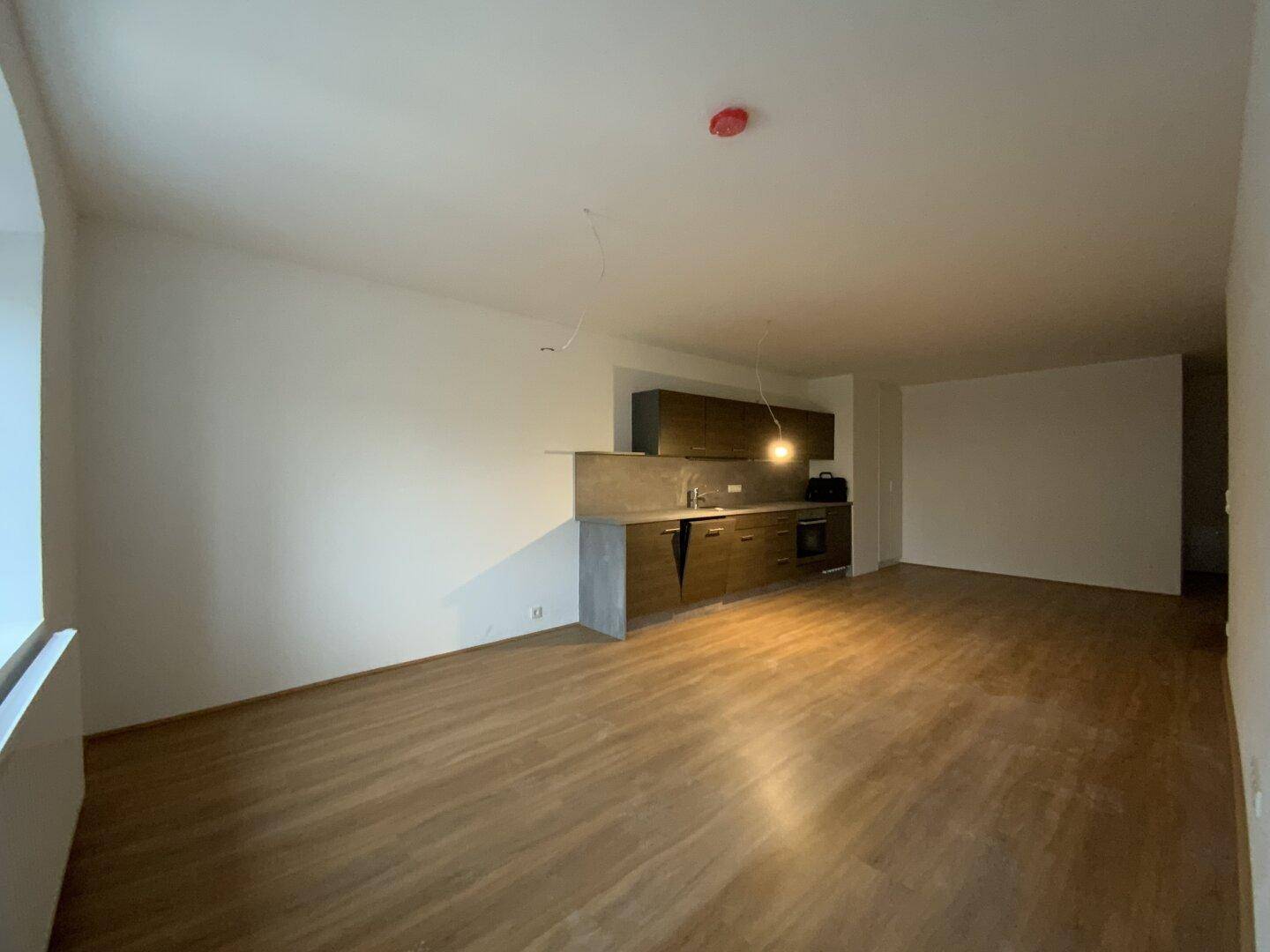 Offener Wohnbereich mit integrierter Küche, Holzboden und viel Platz für individuelle Gestaltung.