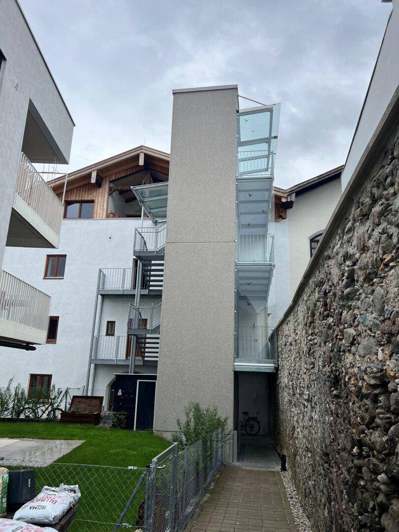 Rückansicht des Gebäudes mit einem externen Glasaufzug und Treppenhaus.