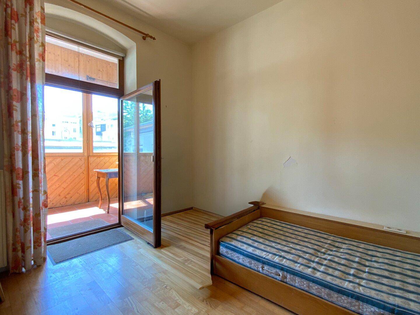 Schlafzimmer mit direktem Zugang zu einem überdachten Balkon oder einer Loggia, hell und luftig.