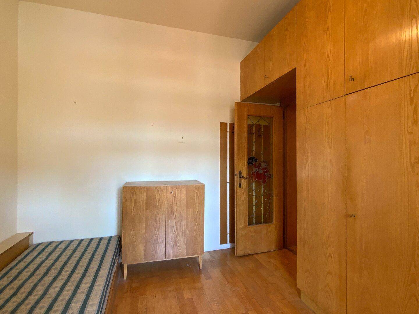 Schlafzimmer mit Einzelbett und passenden Holzmöbeln, ein heller und gemütlicher Raum.
