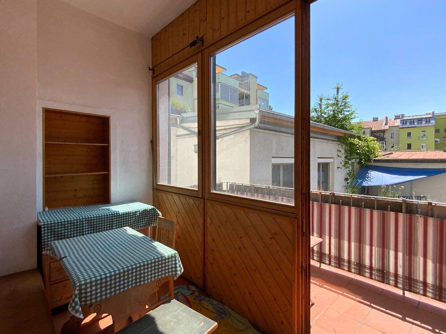 Überdachte Loggia mit Holzverkleidung und Blick auf die umliegenden Gebäude, ideal zum Entspannen.