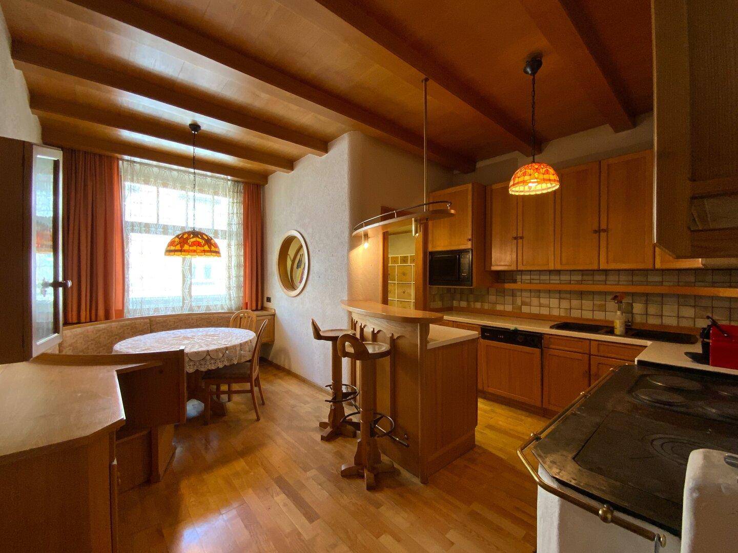 Gemütliche Küche mit Holzbalkendecke, Essbereich und traditionellem Holzofen, ideal für Familienessen.