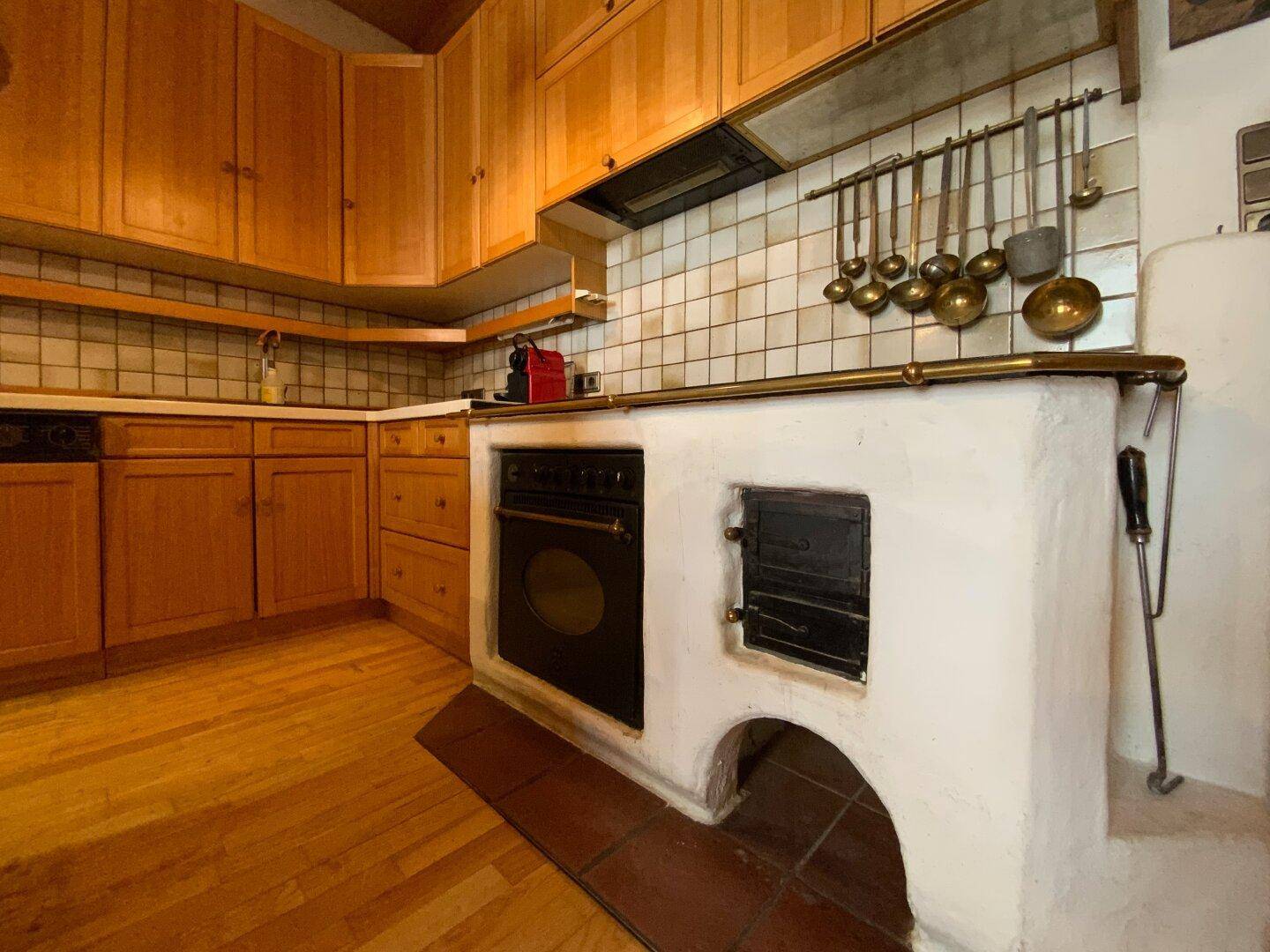 Detailansicht des traditionellen Küchenofens mit Fliesenrückwand und Holzboden, rustikaler Charme.
