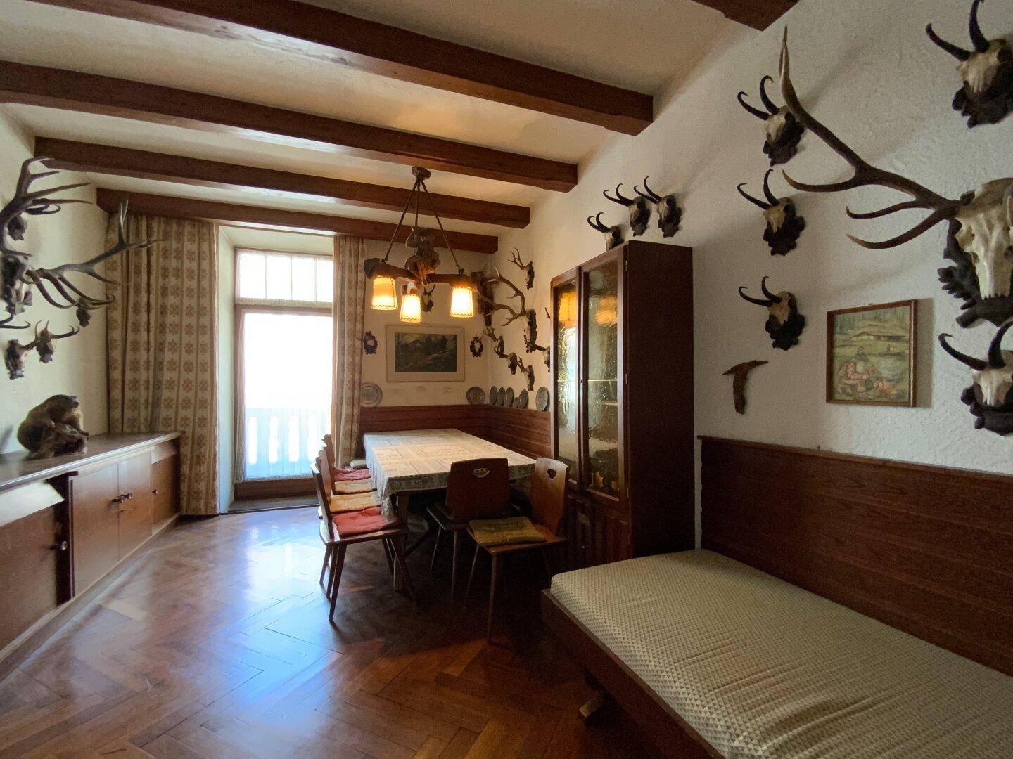 Traditionelles Esszimmer im alpinen Stil mit Hirschgeweihen und großem Esstisch, sehr rustikal.