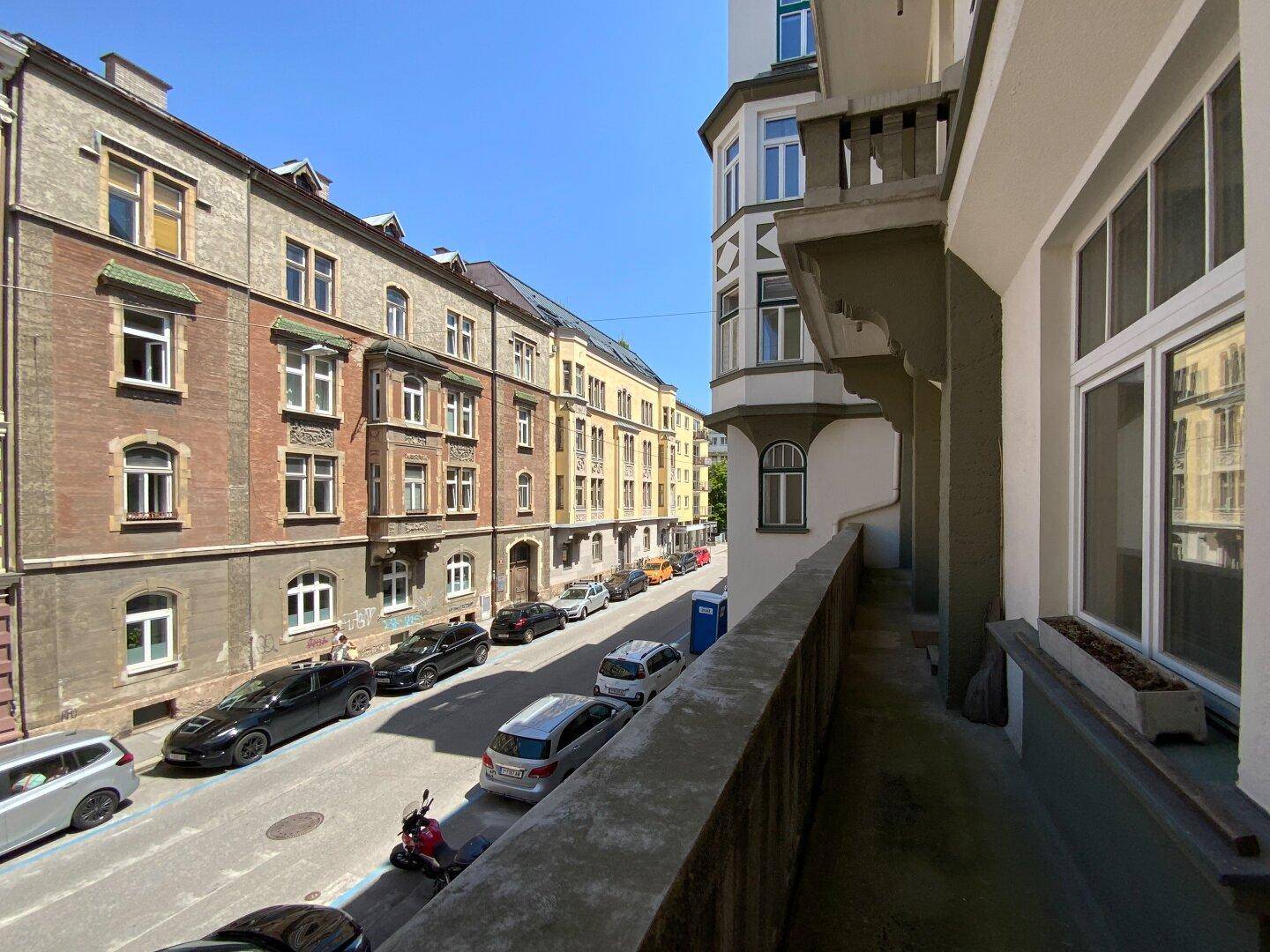 Langer Balkon mit Blick auf die belebte Stadtstraße und umliegende Gebäude.