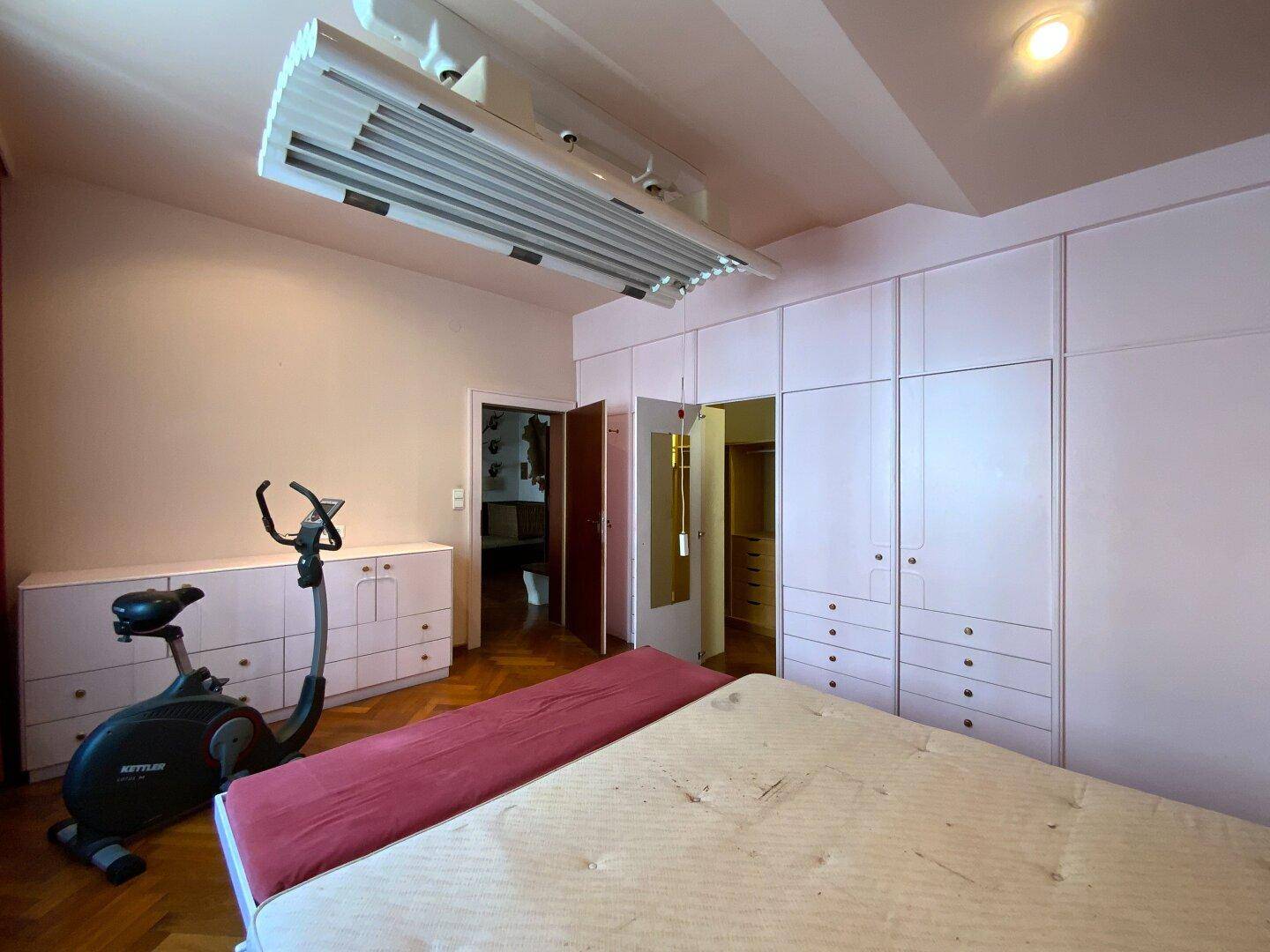 Schlafzimmer mit Einbauschränken, Bett und einem Heimtrainer für Sport, praktisch und geräumig.