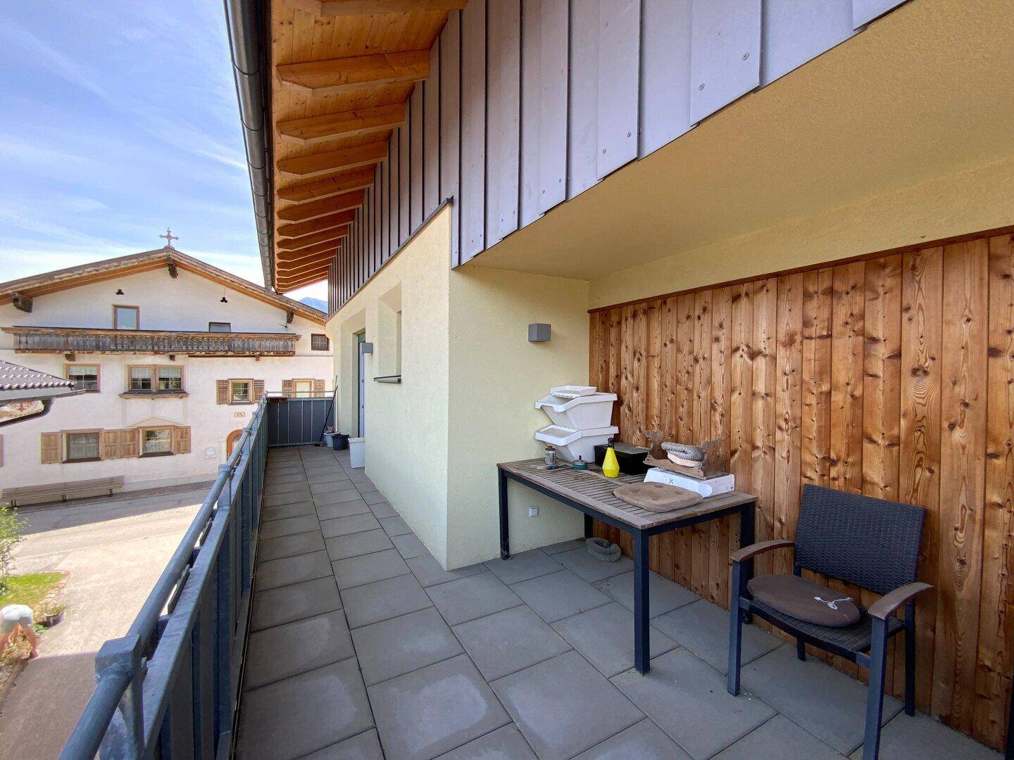 Geräumiger Balkon mit Holzwand und Fliesenboden, ideal für entspannte Stunden im Freien.