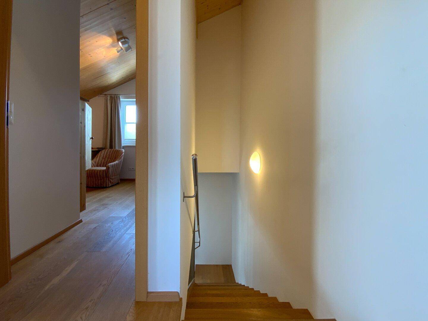 Heller Flur mit Holztreppe und Zugang zu weiteren Räumen im Dachgeschoss.