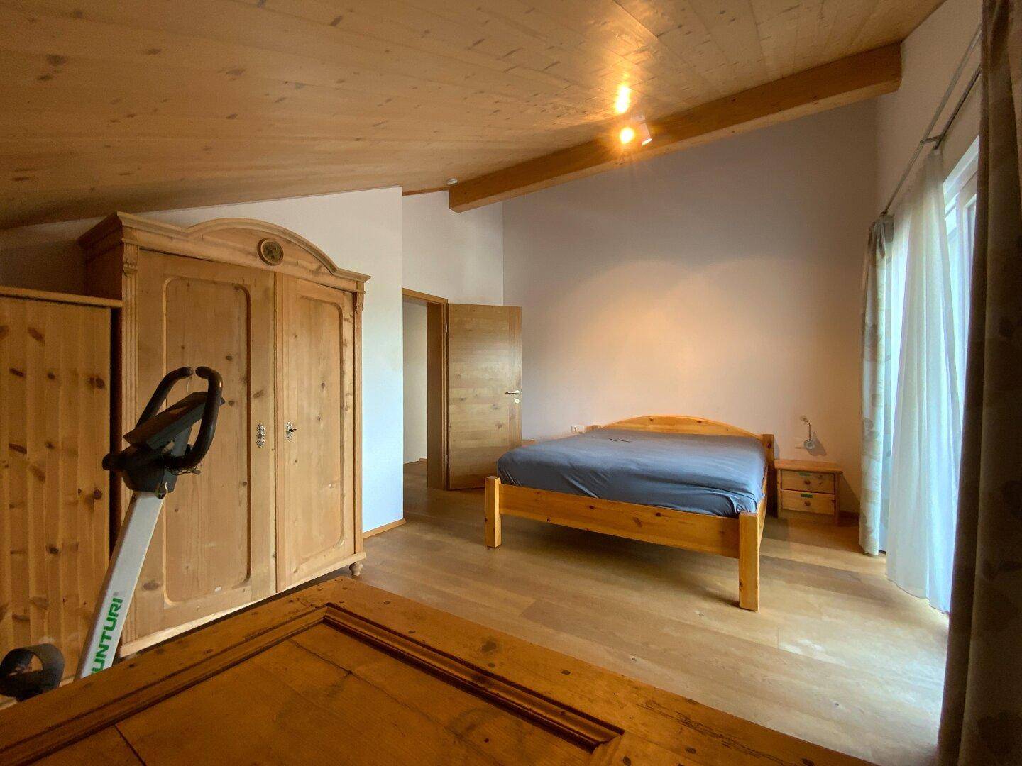 Helles Schlafzimmer mit Holzboden, Dachschräge und großem Kleiderschrank.