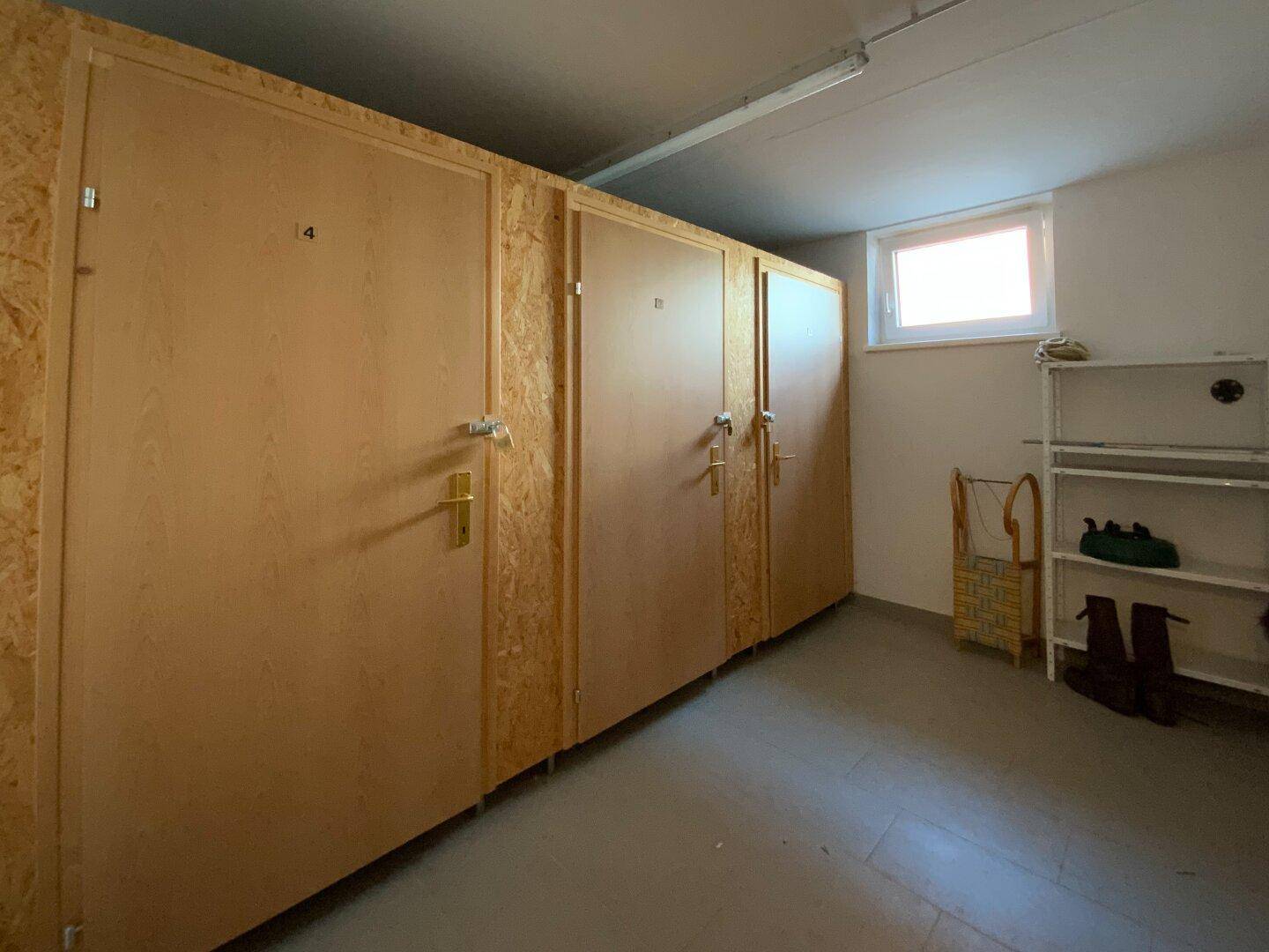 Praktischer Abstellraum mit individuellen Holzverschlägen und einem kleinen Fenster für Tageslicht.
