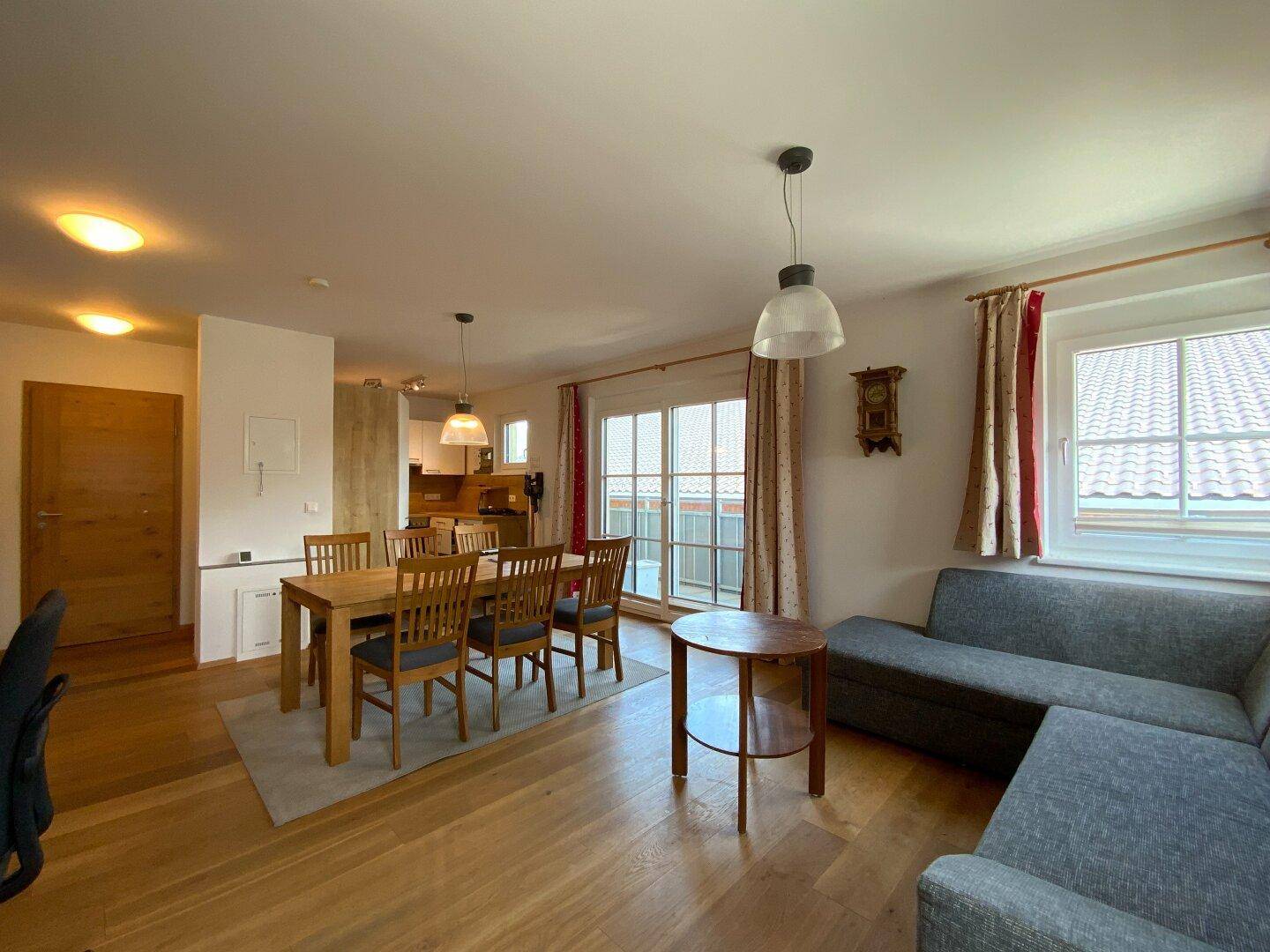 Heller Wohn-Essbereich mit Holzboden, Zugang zum Balkon und gemütlicher Sitzecke.