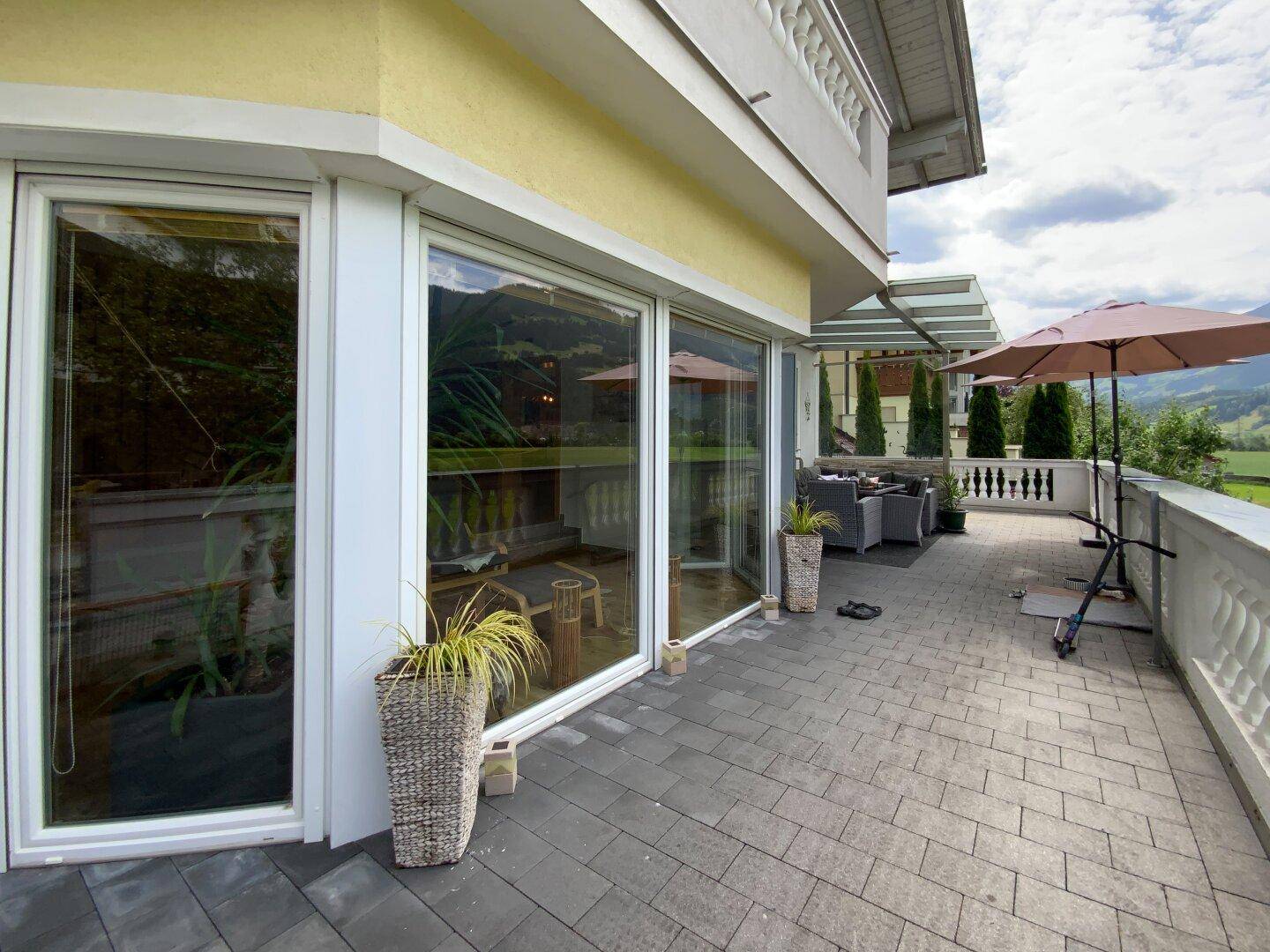 Große Terrasse mit bodentiefen Fenstern, die viel Licht ins Innere lassen und einen schönen Ausblick bieten.