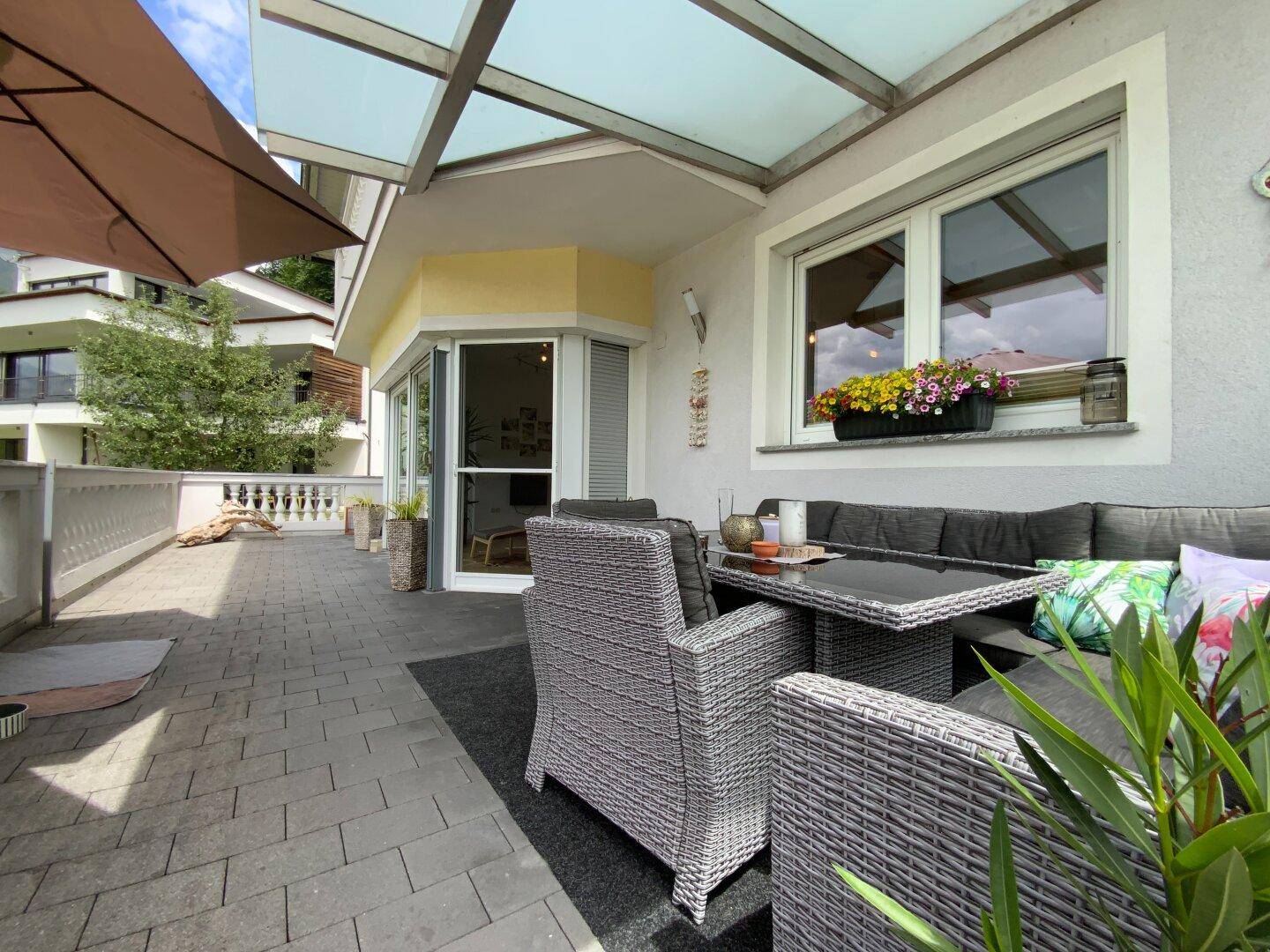 Große, überdachte Terrasse mit bequemen Outdoor-Möbeln und Blick auf die Umgebung.