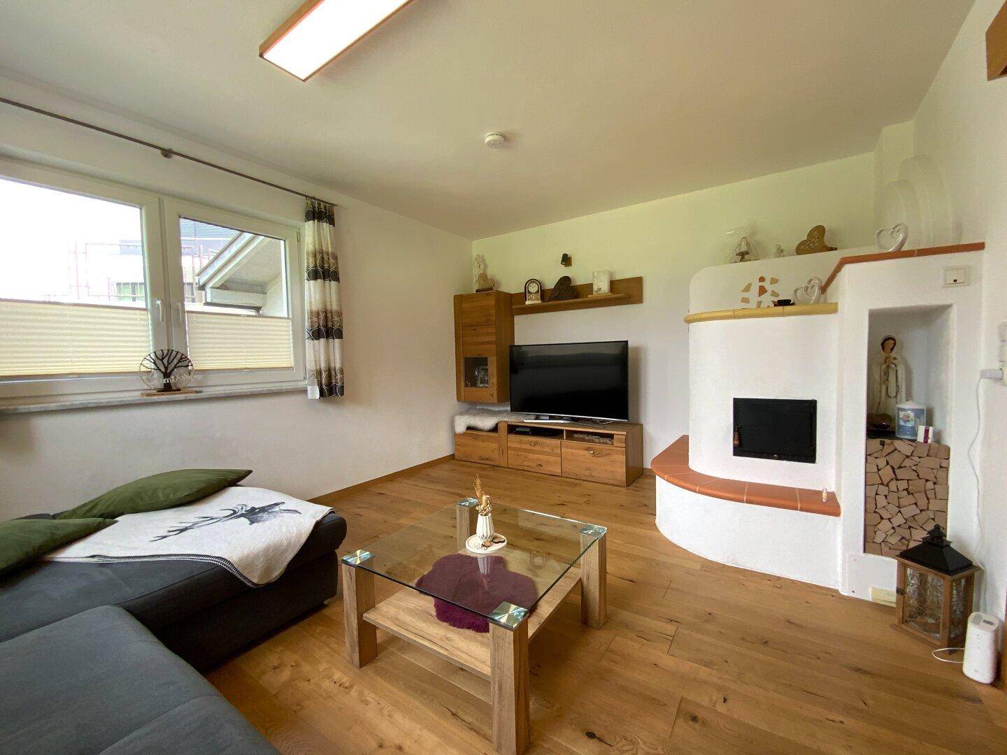 Wohnzimmer mit Kachelofen, Holzboden und bequemer Sitzecke, ideal für kalte Abende.