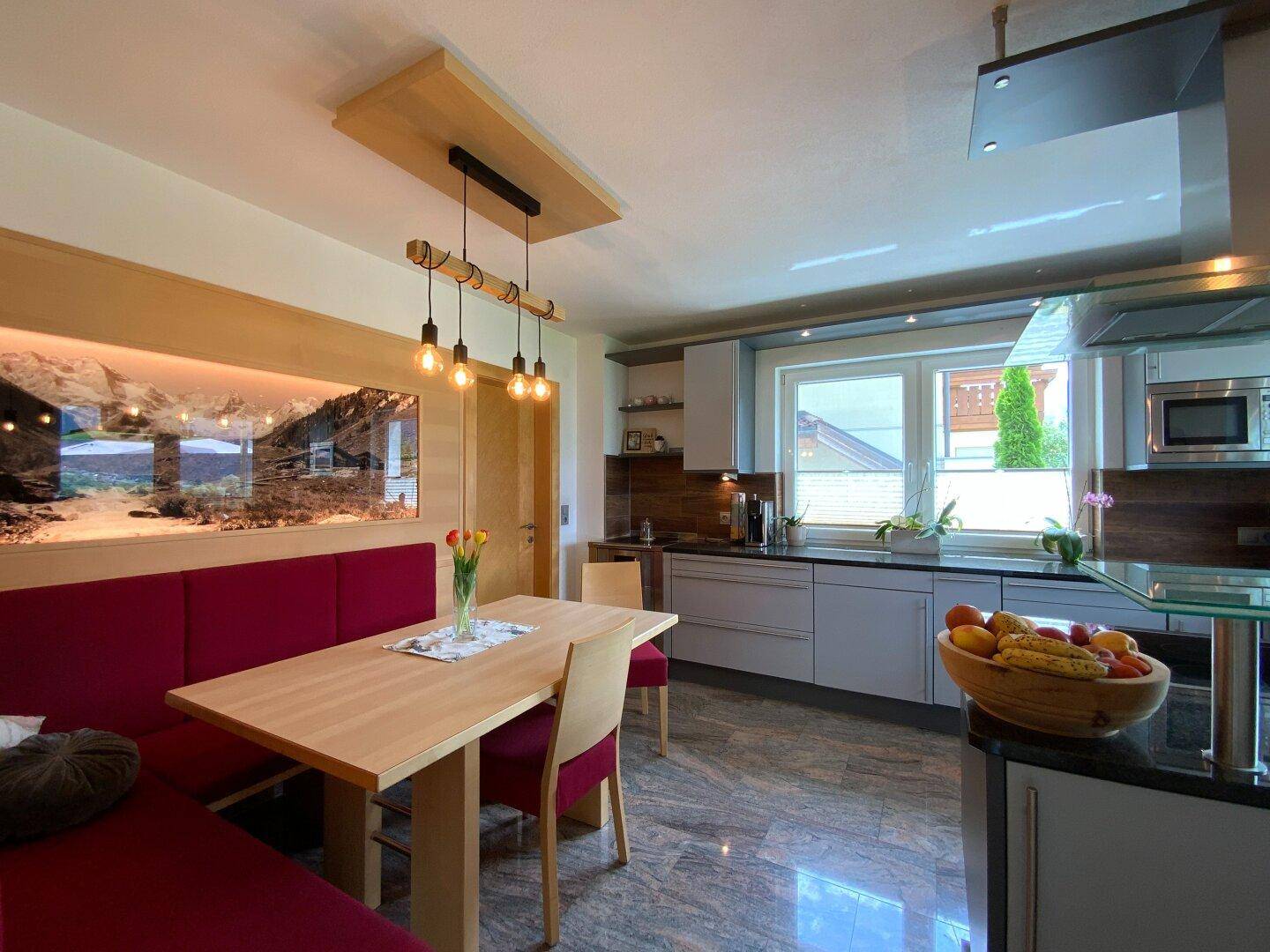 Moderne Wohnküche mit Essbereich, Holztisch und roten Sitzbänken, ideal für Familienmahlzeiten.