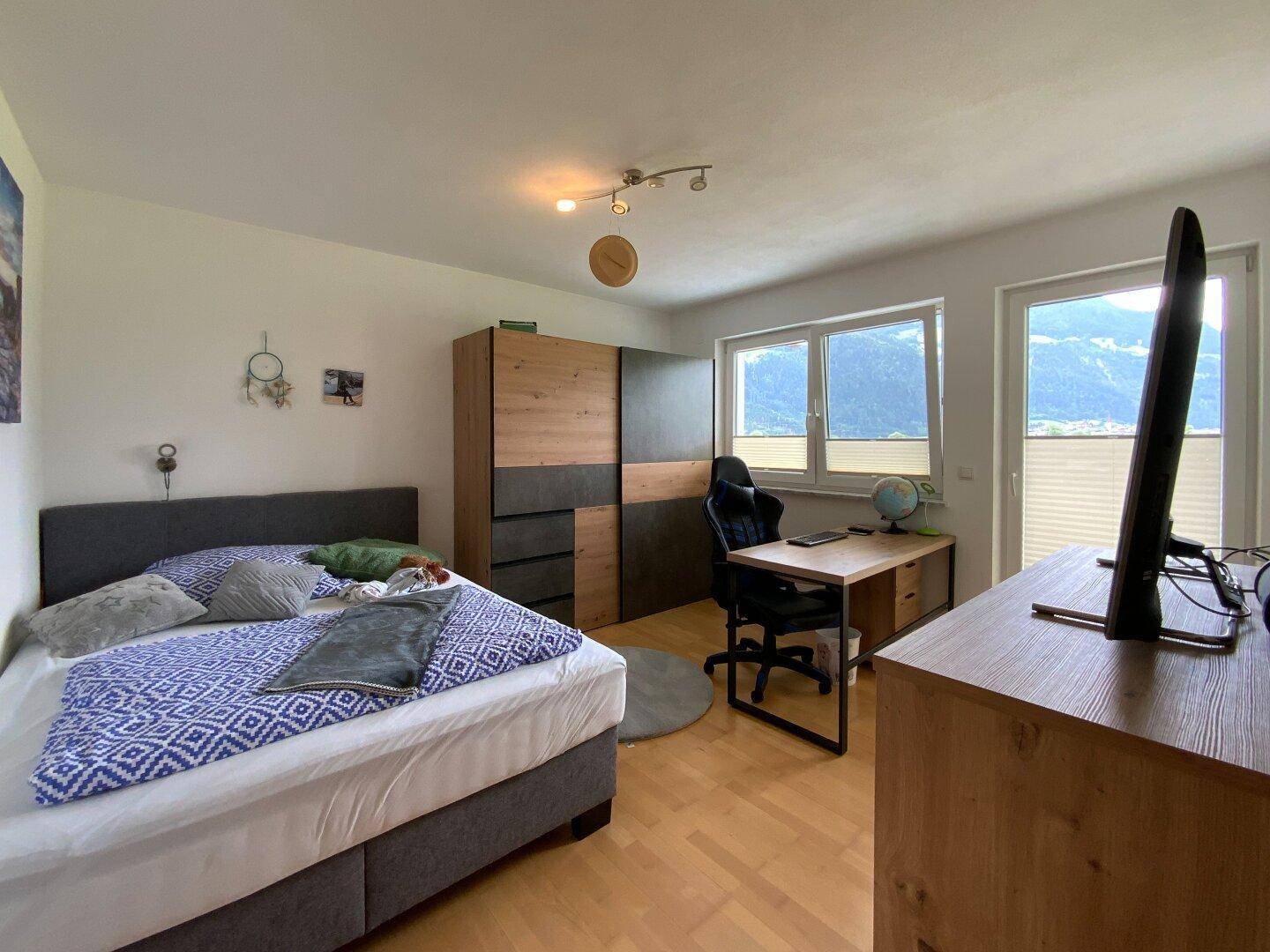 Geräumiges Schlafzimmer mit Holzboden, Schreibtisch und einem schönen Blick auf die umliegenden Berge.