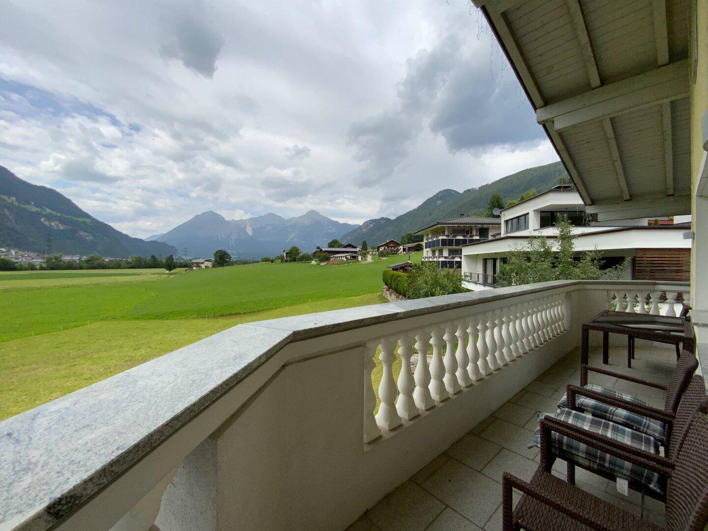 Geräumiger Balkon mit bequemen Gartenmöbeln und weitem Panoramablick über das Tal und die Berglandschaft.