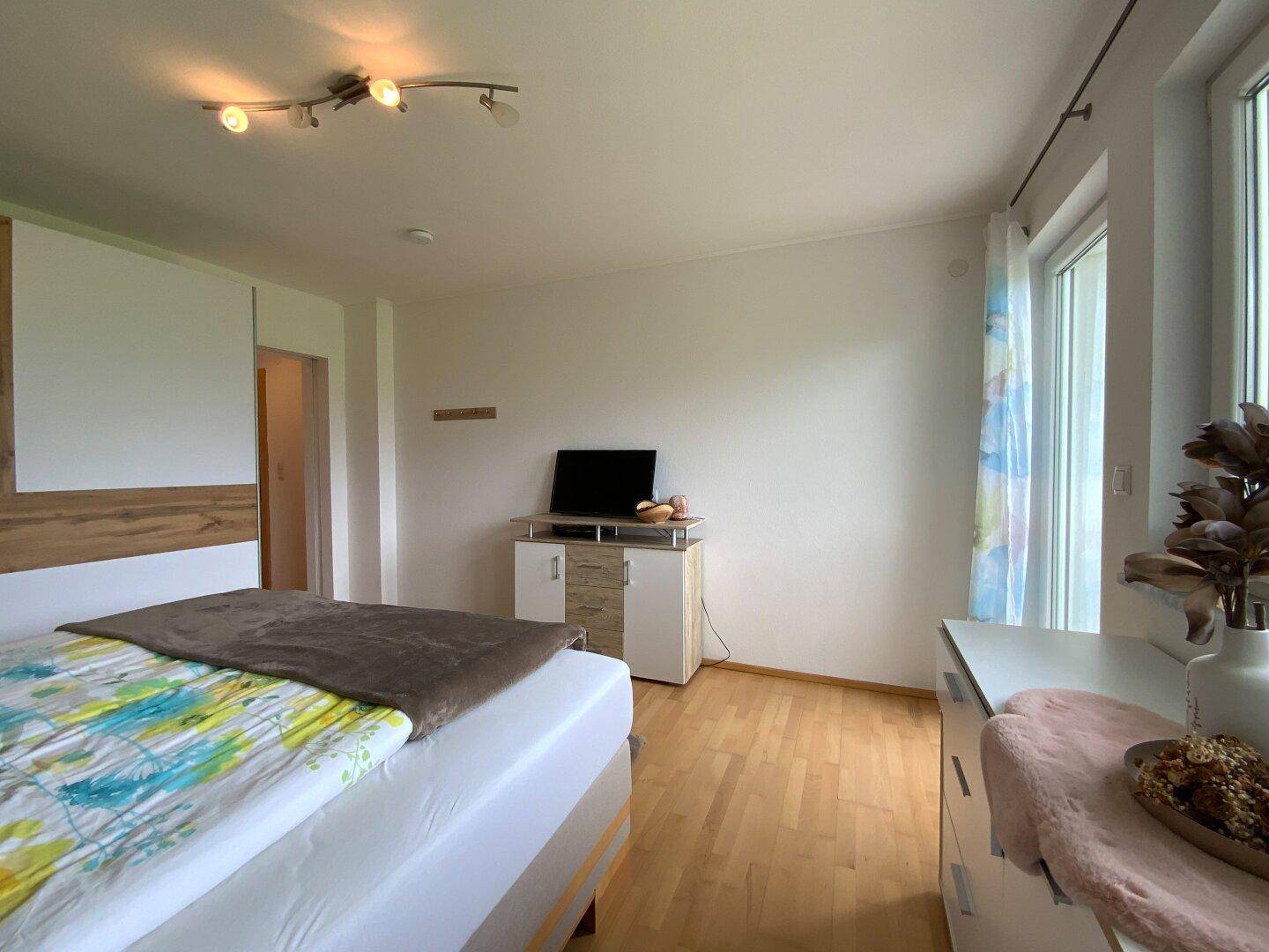 Gemütliches Schlafzimmer mit Holzboden und einem TV-Möbel, das eine entspannte Atmosphäre schafft.
