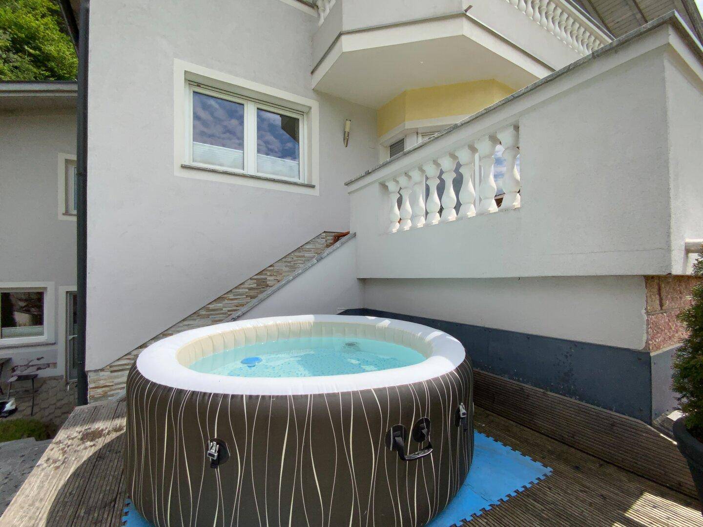 Aufblasbarer Whirlpool auf einer Holzterrasse, bereit für entspannende Momente im Freien.