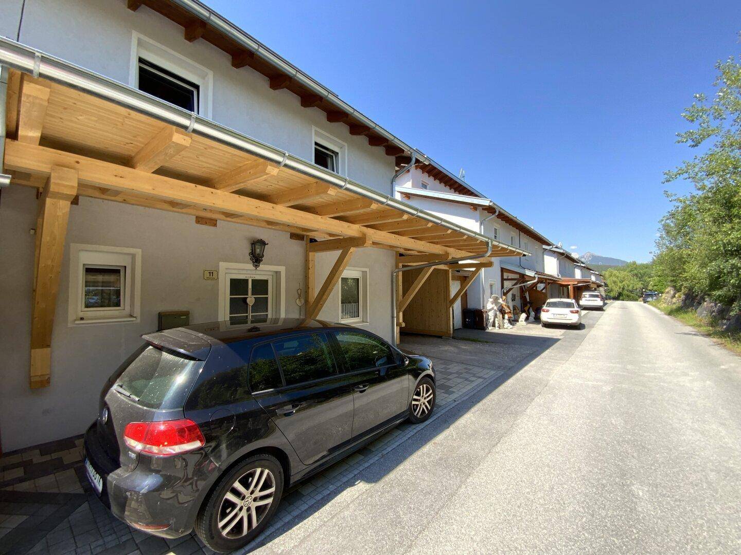 Reihe von Häusern mit hölzernen Carports entlang einer ruhigen Straße.