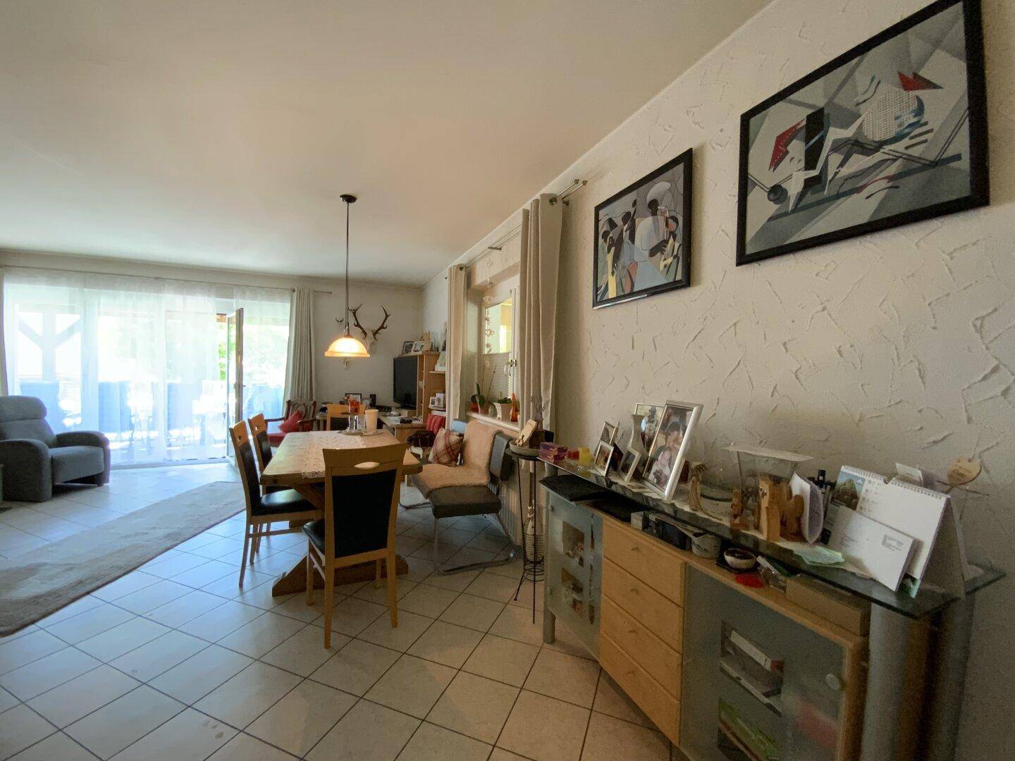 Heller Wohn-Essbereich mit Sideboard, Esstisch und Zugang zu einem sonnigen Außenbereich.
