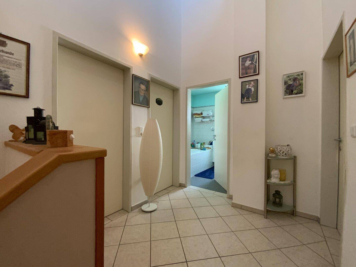 Heller Flur im Obergeschoss mit Fliesenboden und Zugang zu mehreren Zimmern, inklusive Bad.
